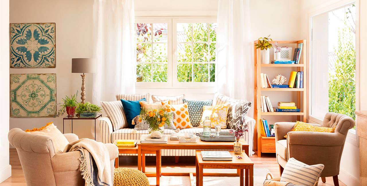 Salón en tonos beige, muebles de madera, cojines de colores, sofá a rayas, butacas y suelo de parquet