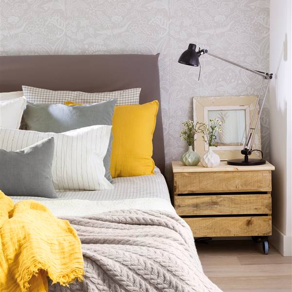 Semitoma de dormitorio con papel pintado y cama con cojines y mesilla de noche hecha con caja de madera_ 00452077