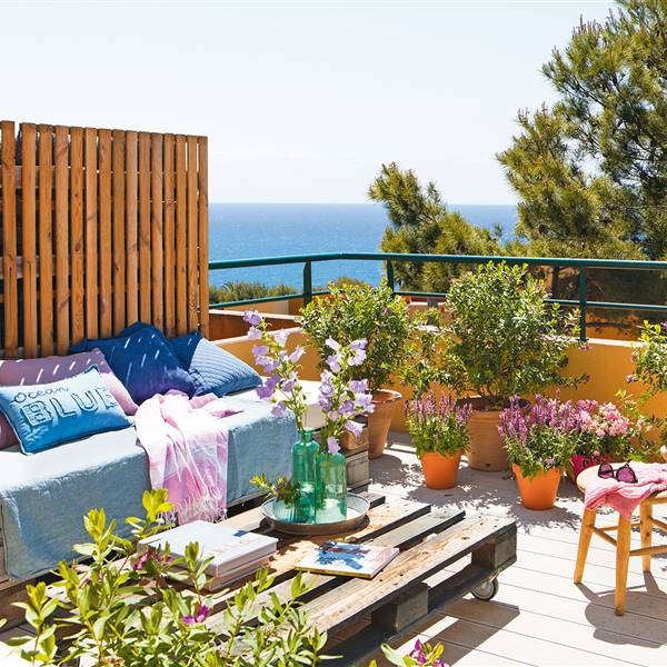 Terraza con sofá mesa de centro y plantas