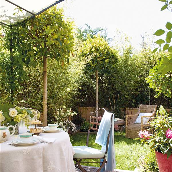 Zona de estar en el jardín con pérgola y mesa con mantel rosa
