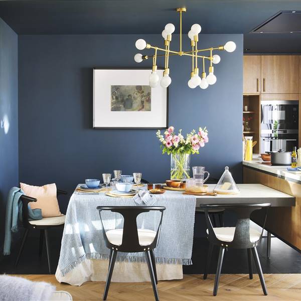 Comedor en azul con lámpara dorada y mesa con sillas negras 