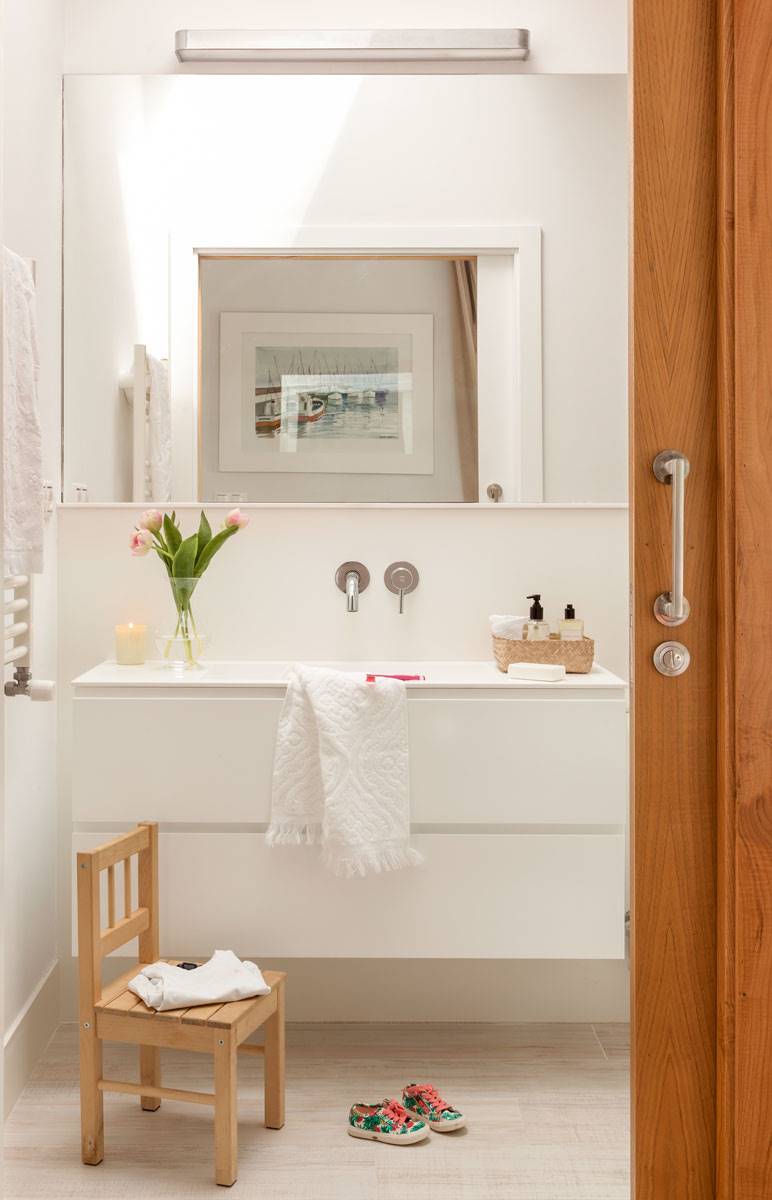Baño con mueble blanco suspendido y gran espejo con aplique. 
