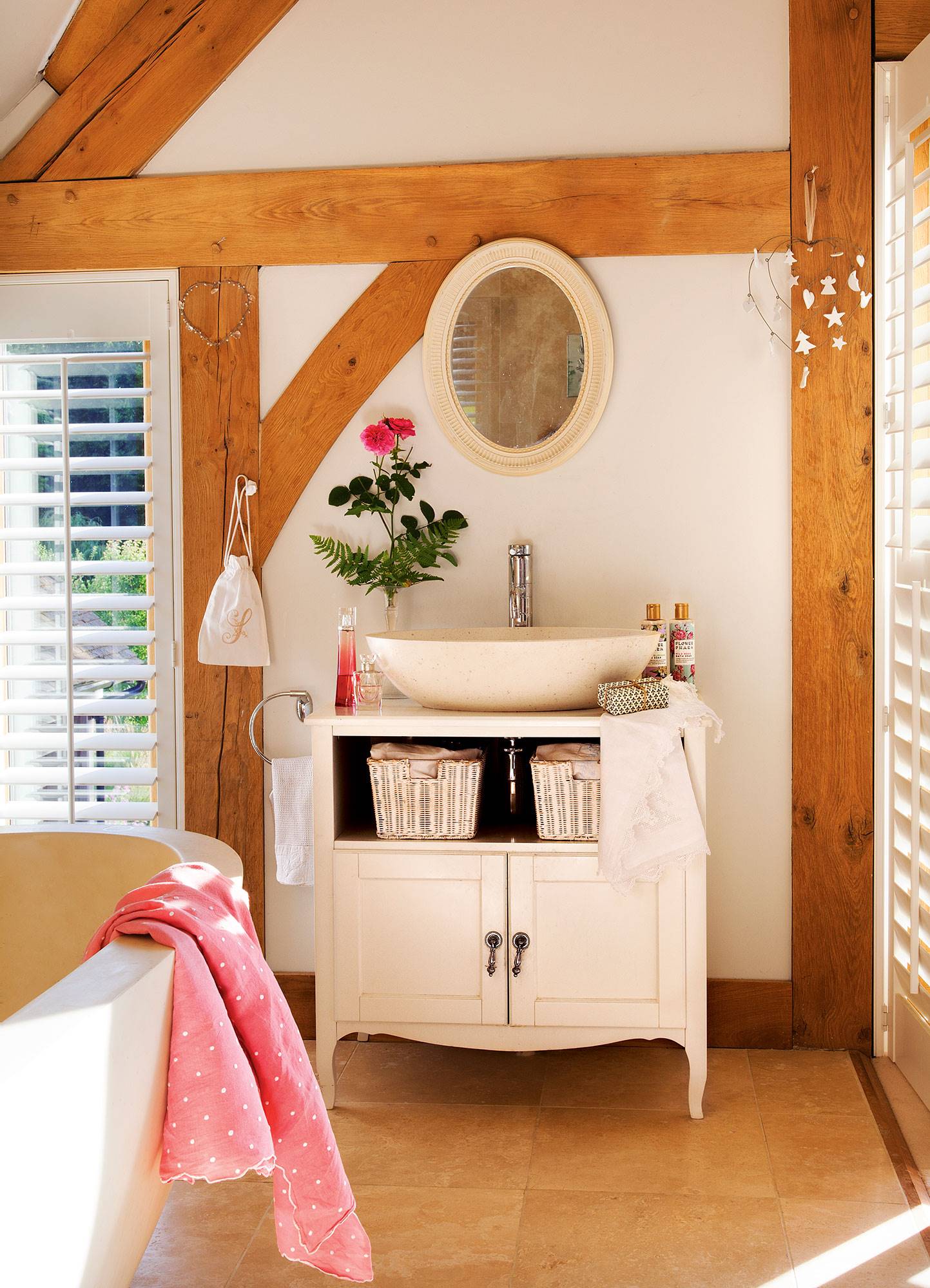 Baño con vigas de madera y mueble de baño blanco. 