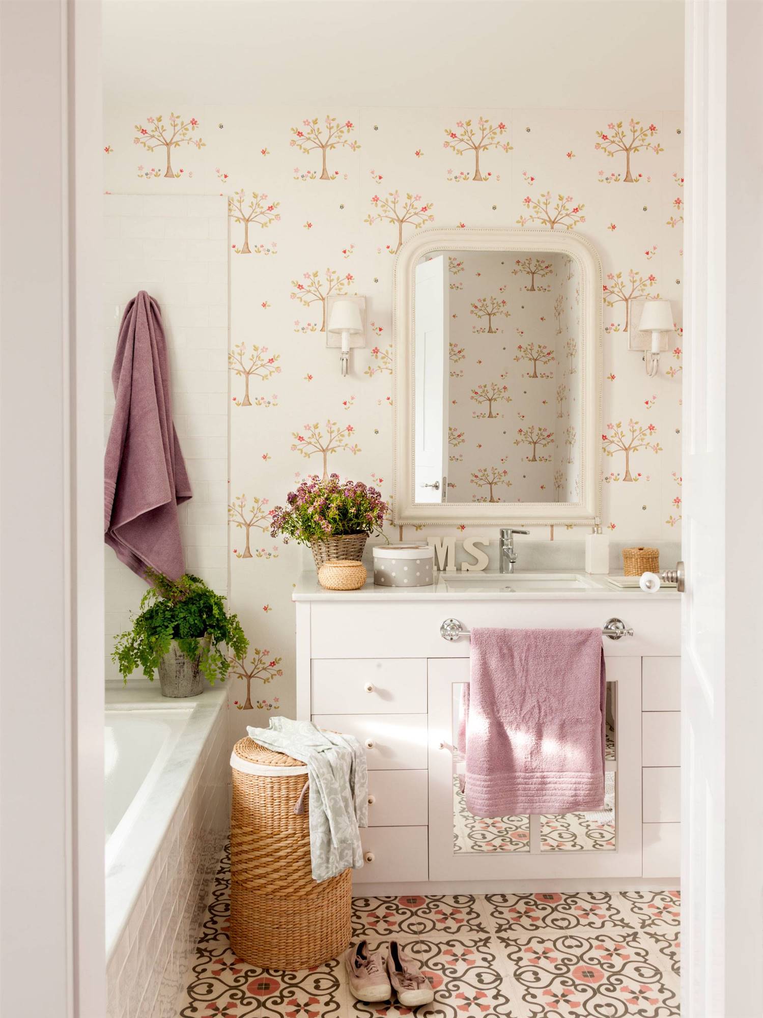 Baño con mueble blanco y papel pintado floral. 