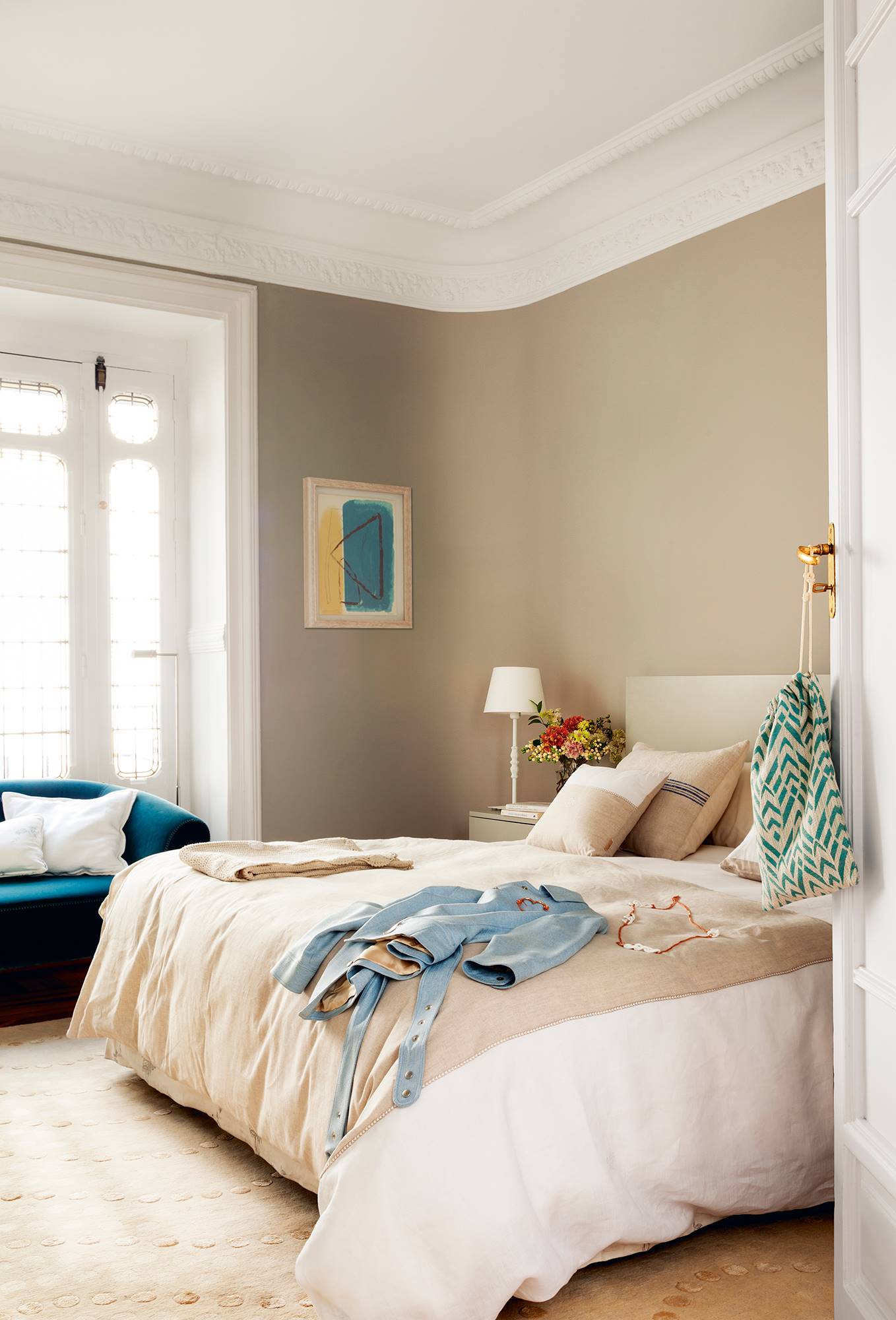 Dormitorio principal con cama grande, pared beige y molduras.