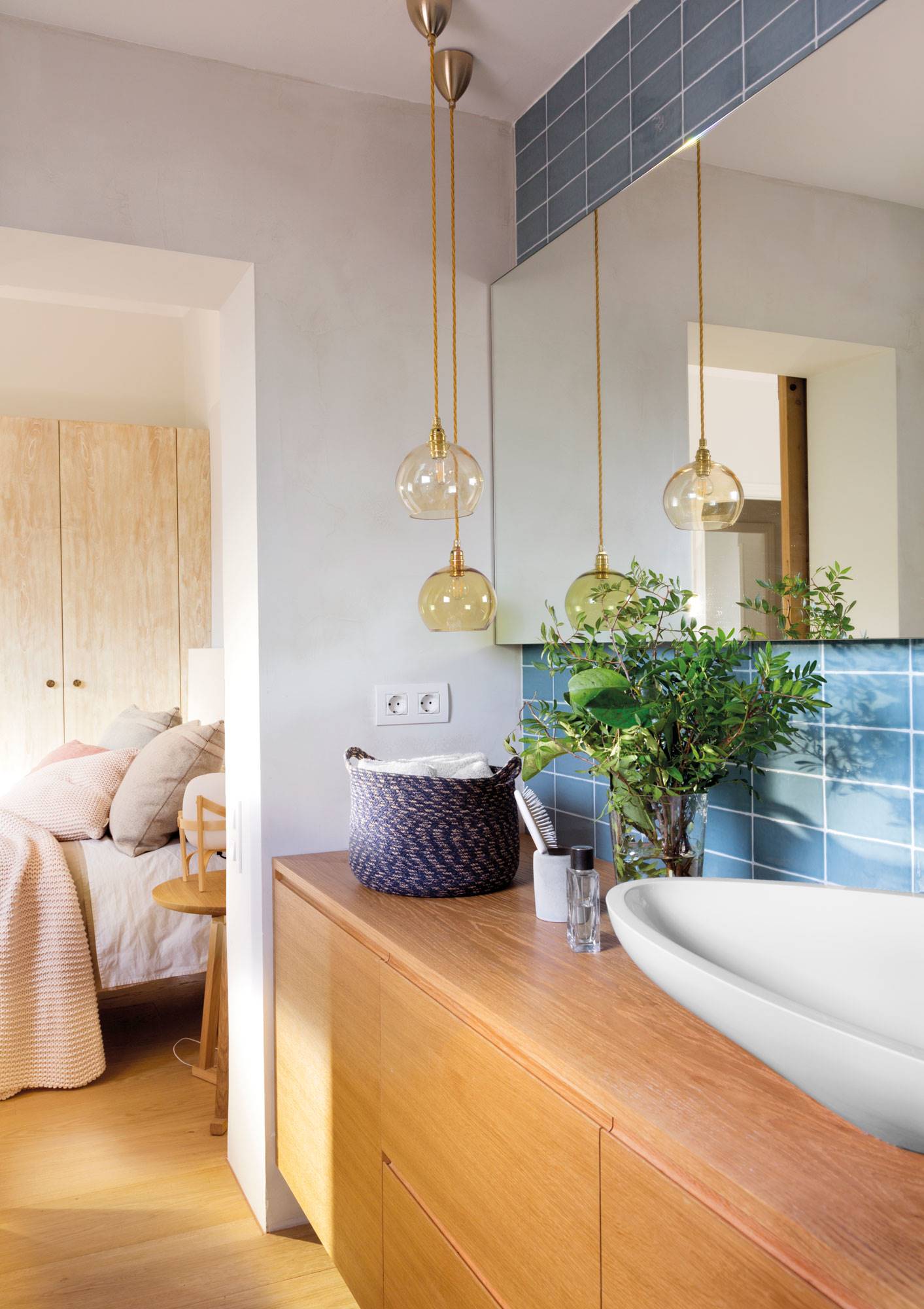 Baño con mueble de madera y revestimiento de azulejos azules. 