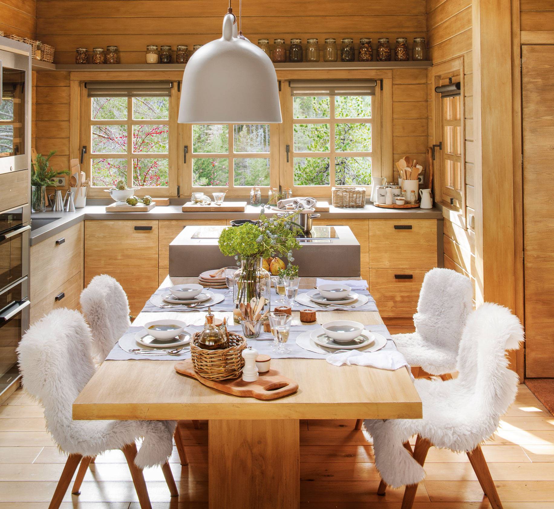 Comedor rústico en la cocina con mesa de madera y sillas con mantas de piel