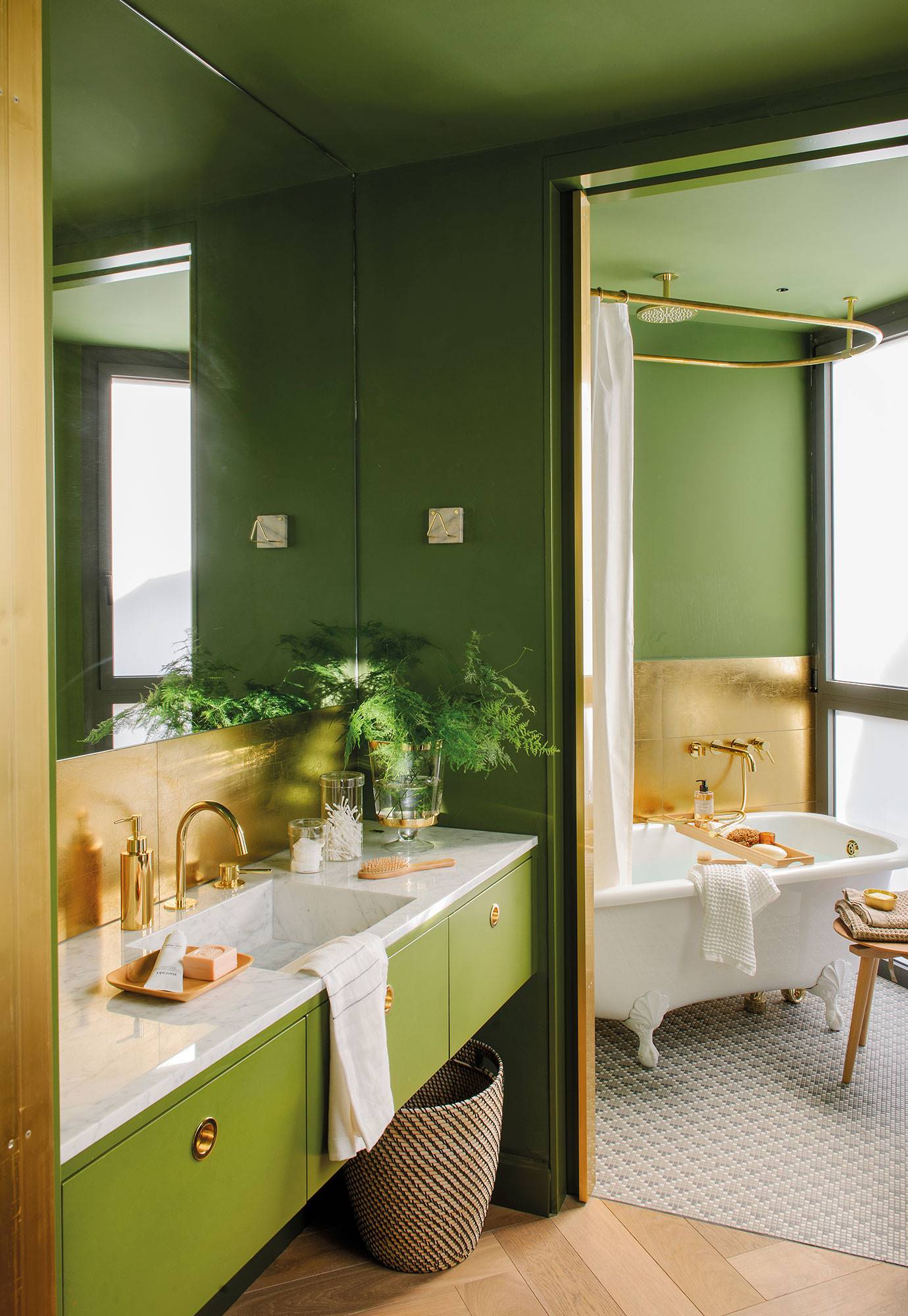 Baño con paredes y mueble de color verde, encimera de mármol y antepecho y grifería dorados.