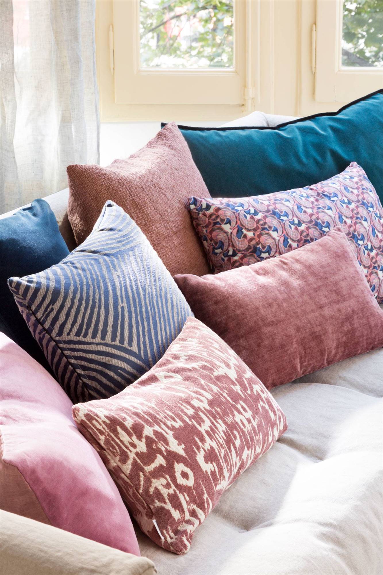 Sofá con cojines estampados en tonos azules, rosas y blancos. 