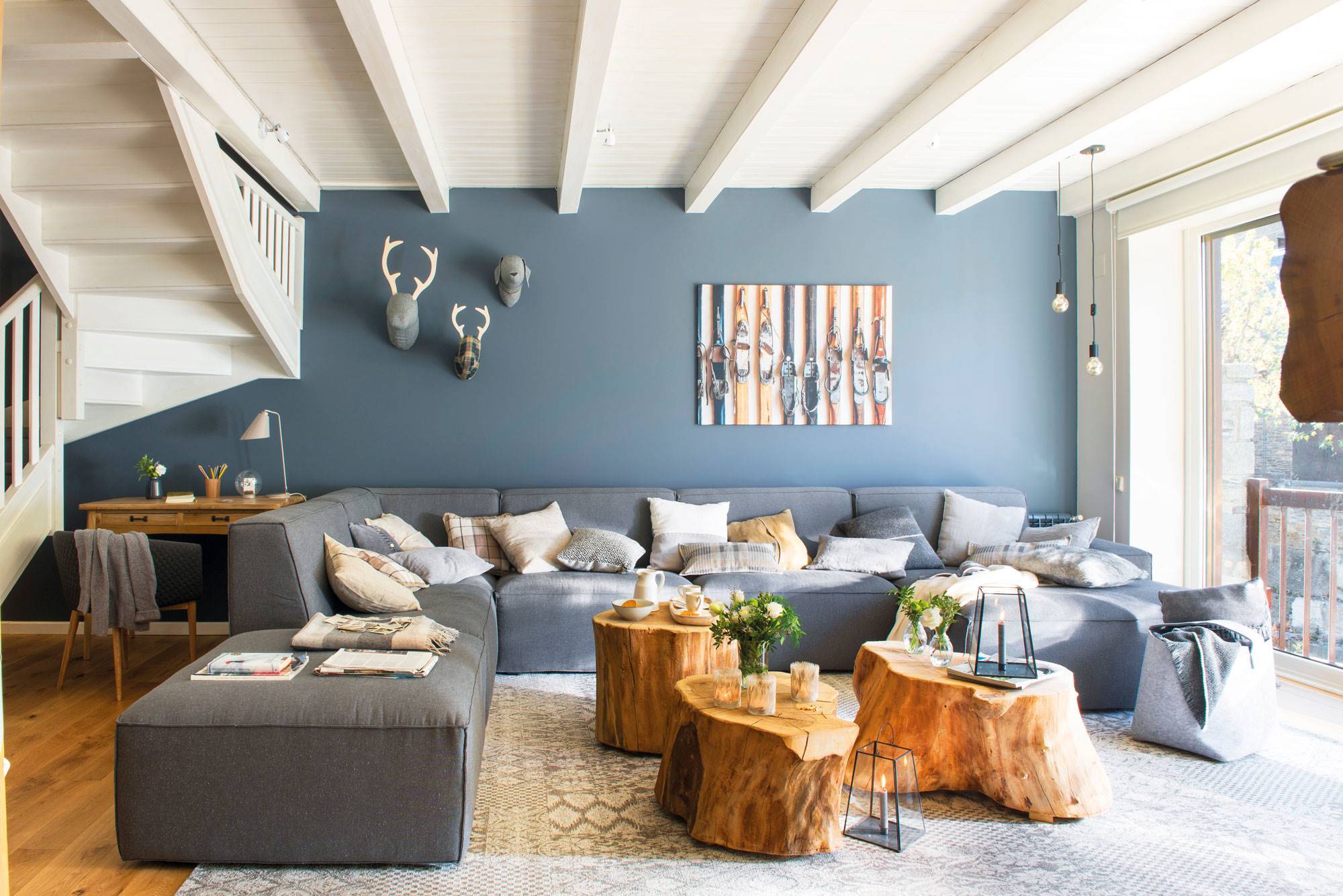 Salón rústico moderno con pared azul y sofá de color gris. 