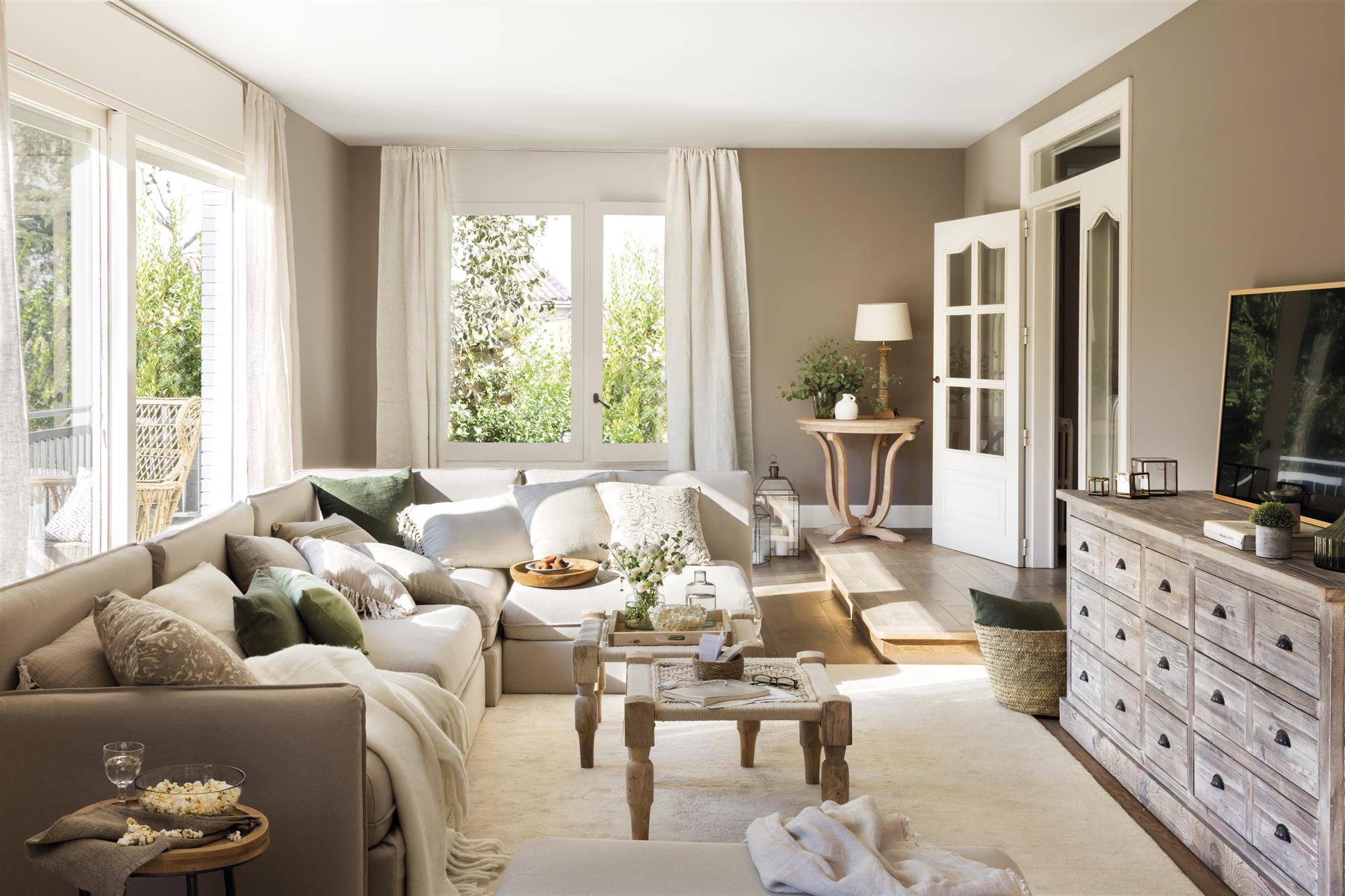 Salón con sofá con chaiselongue y gran cómoda de madera.