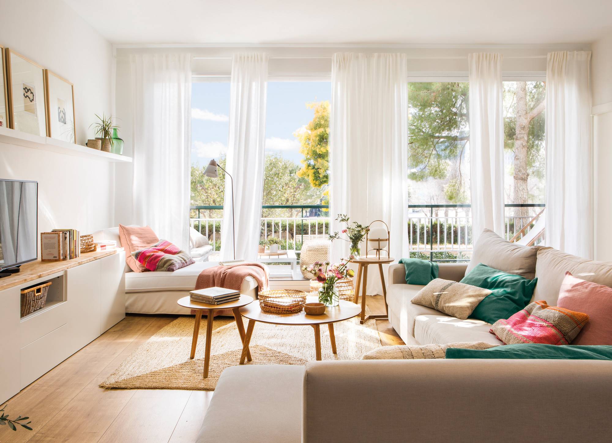 Salón con sofá beige, mueble de la televisión blanco y con un gran ventanal que comunica con la terraza. 