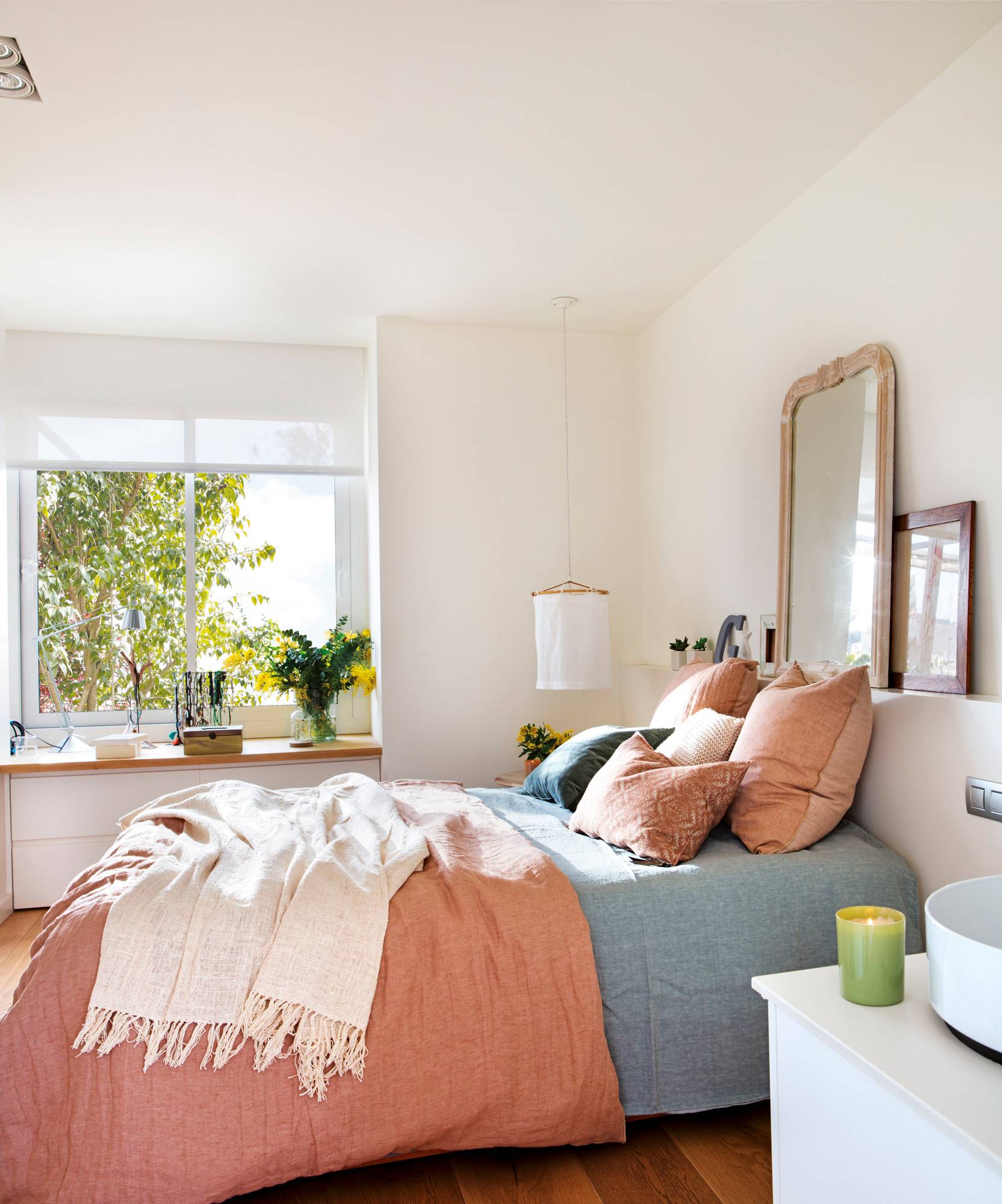 Dormitorio primaveral con colores empolvados y cómoda debajo de la ventana