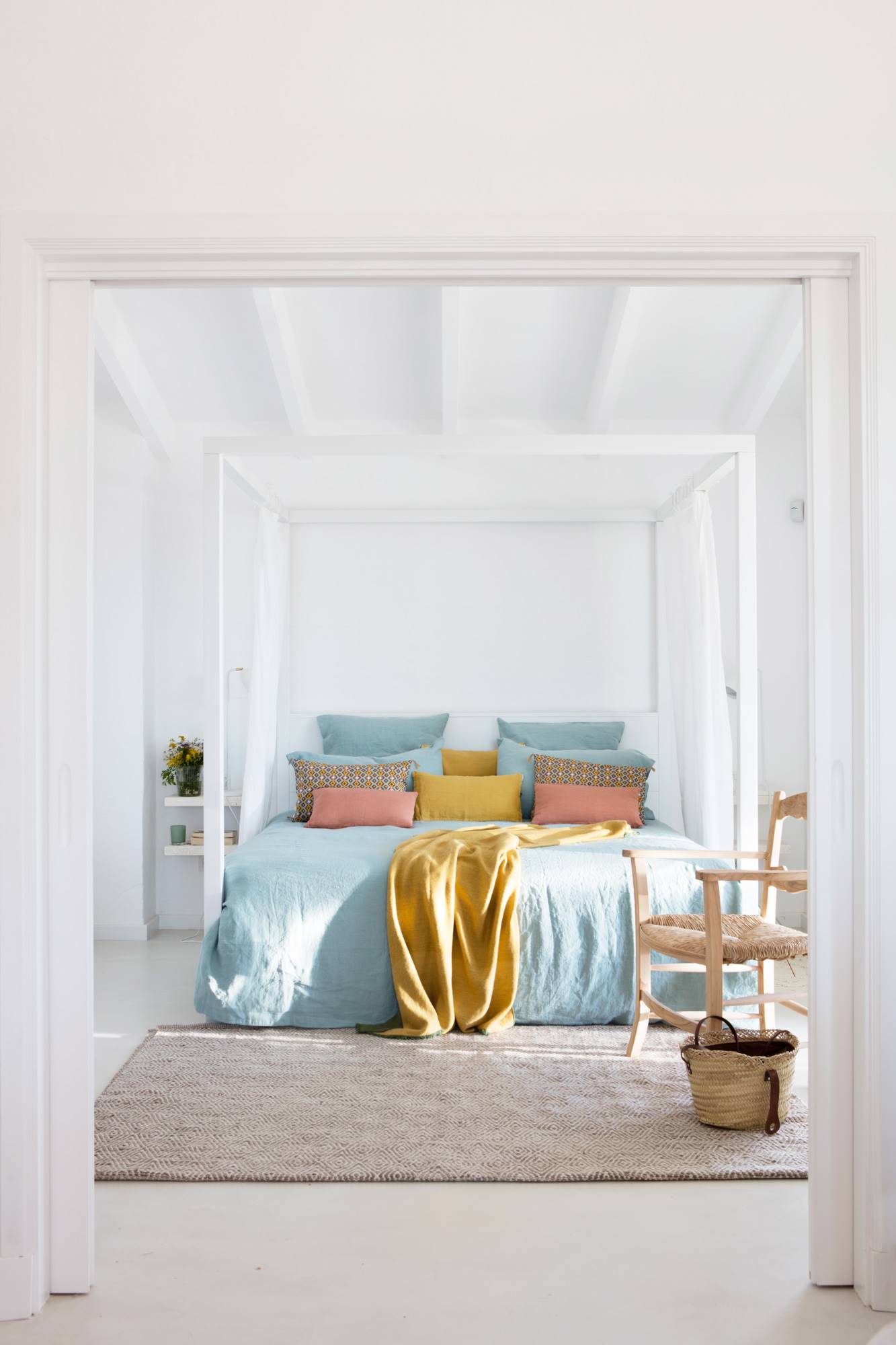 Dormitorio de primavera  con dosel blanco y ropa de cama en azul, gris y rosa.