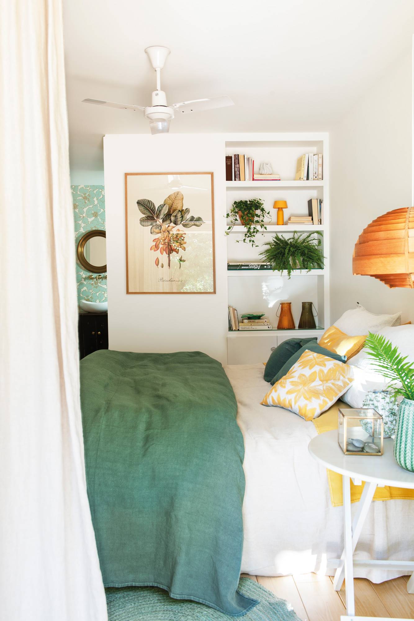 Dormitorio de primavera con ropa de cama verde y mini librería de obra.