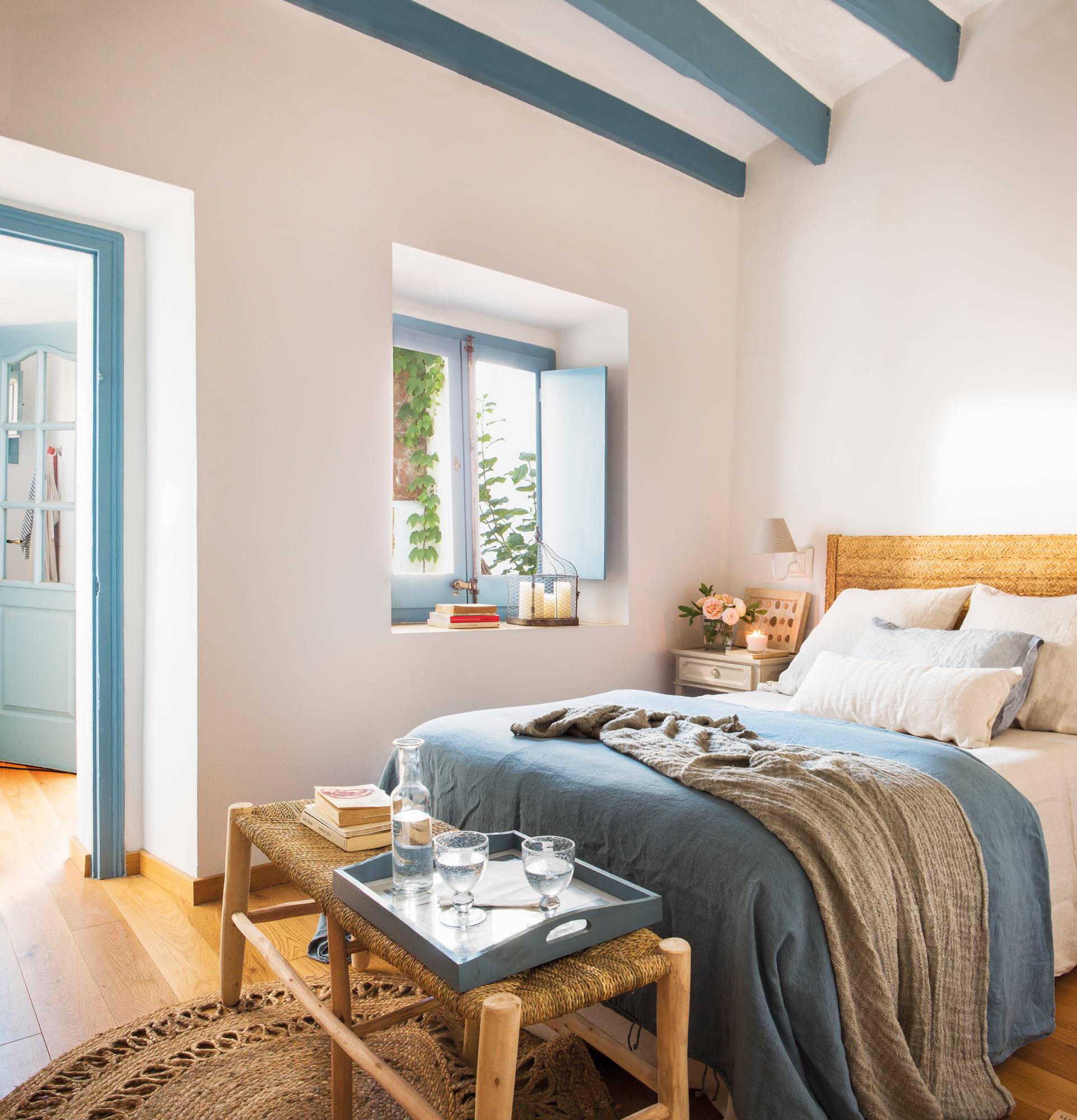 Dormitorio muy veraniego con vigas azules y paredes blancas