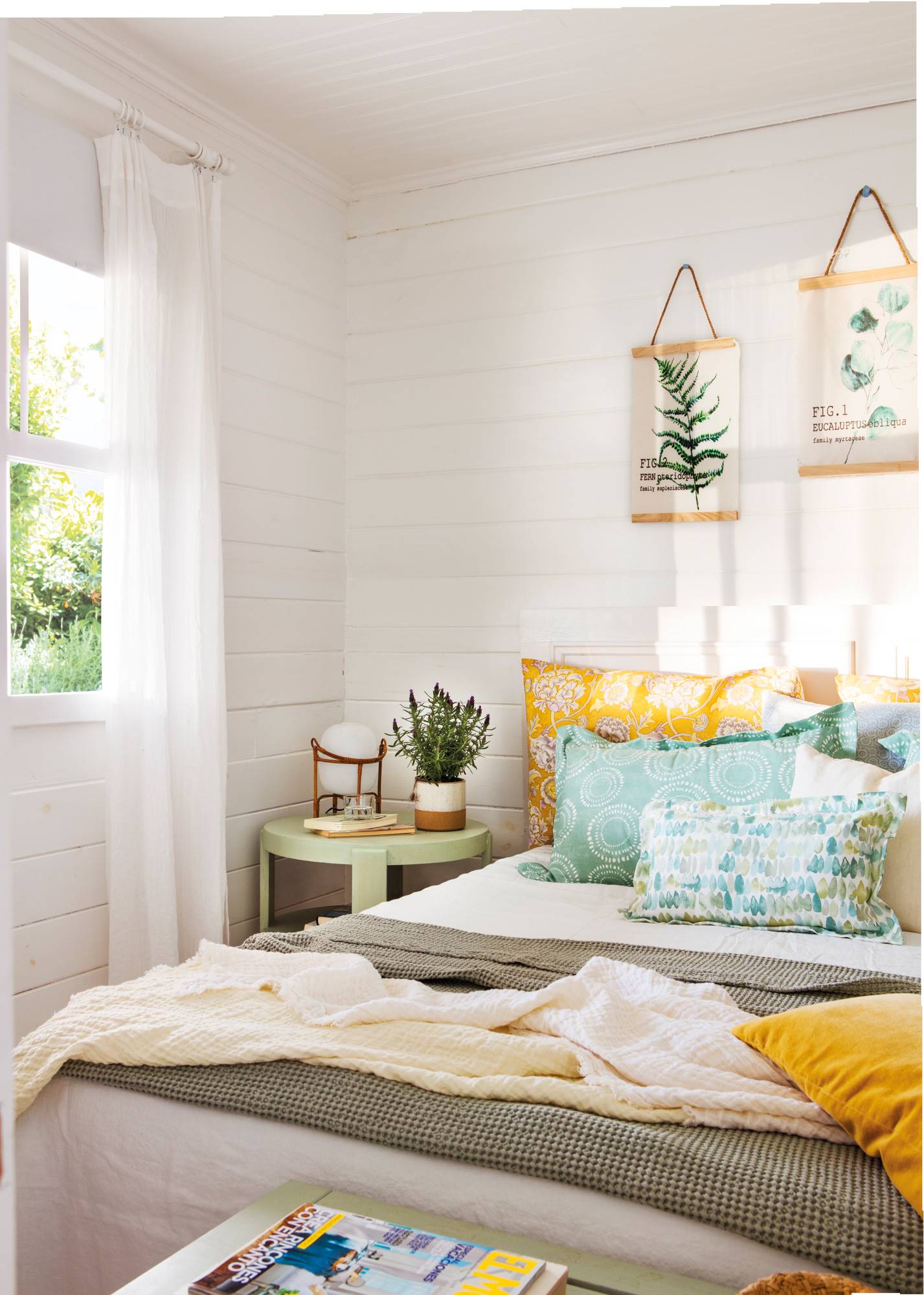 Dormitorio de primavera con listones de madera horizontales, mesita de noche lacada de verde y cuadros de plantas en la pared del cabecero.