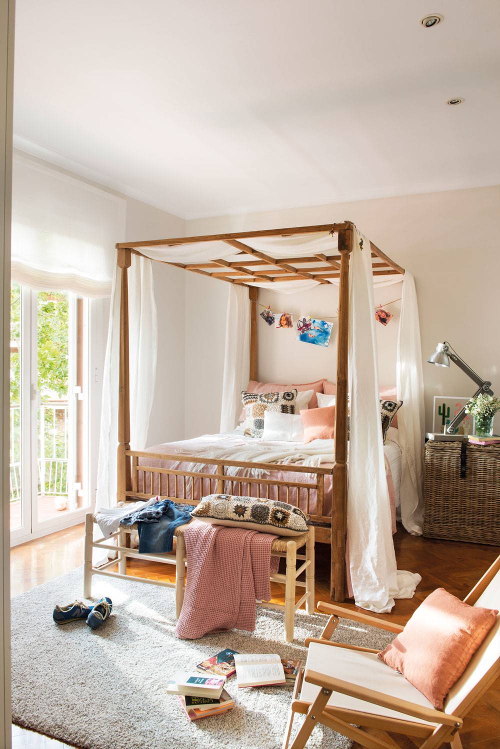Dormitorio de primavera con cama con dosel y baúl de fibra como mesilla.