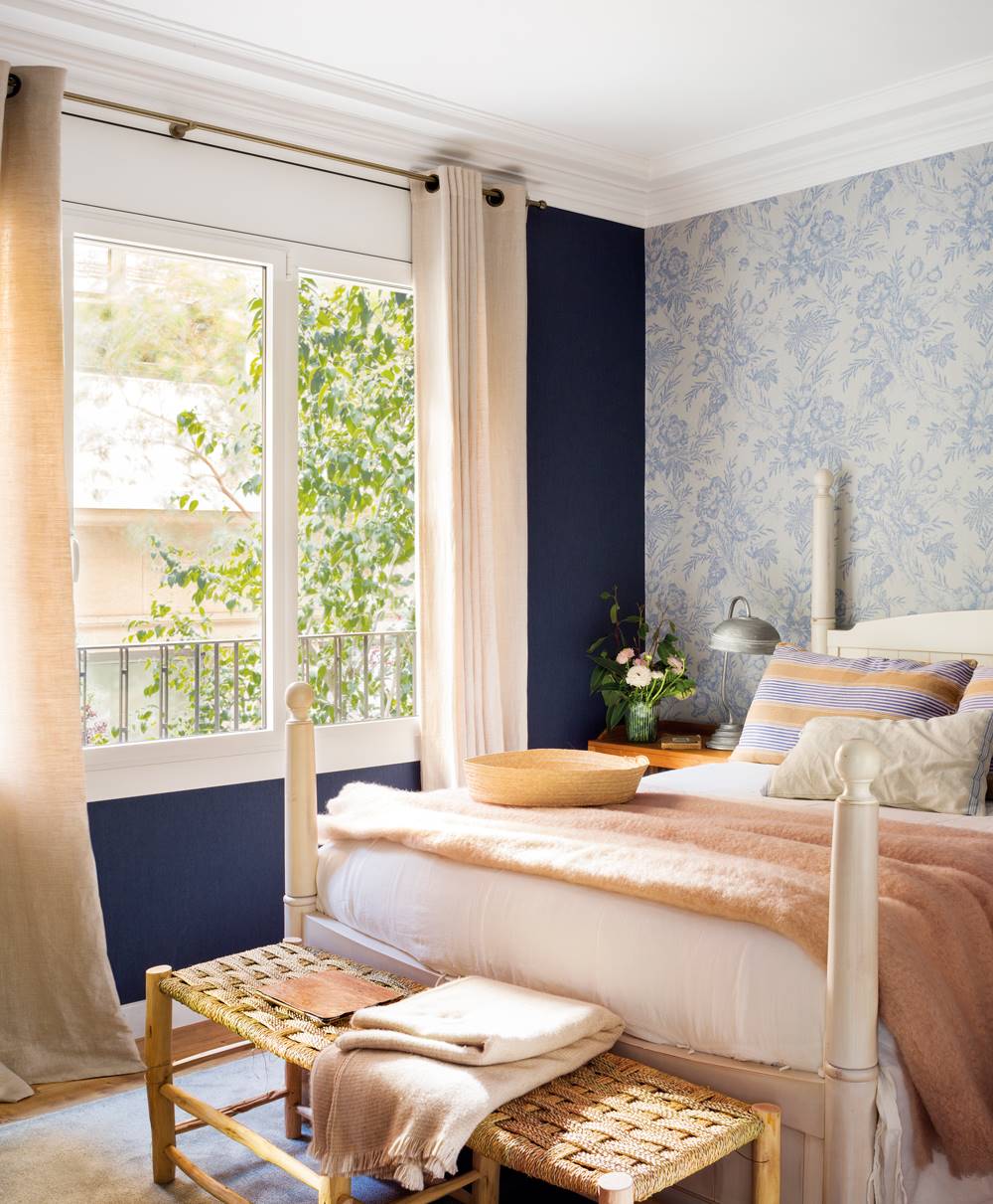 Dormitorio con cama blanca y combinación de dos papeles pintados: liso azul y con motivos