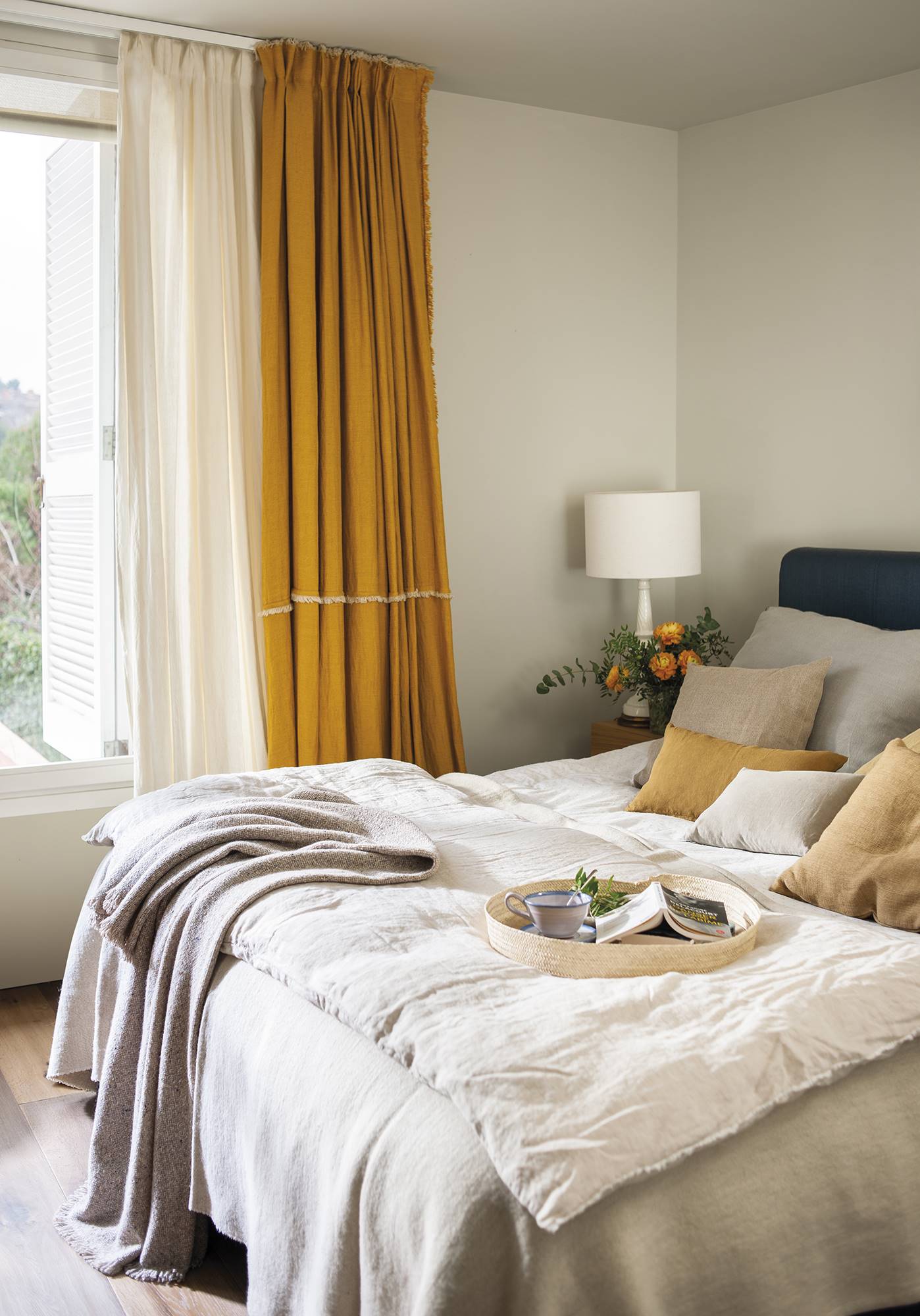Dormitorio con cabecero tapizado y dobles cortinas. 