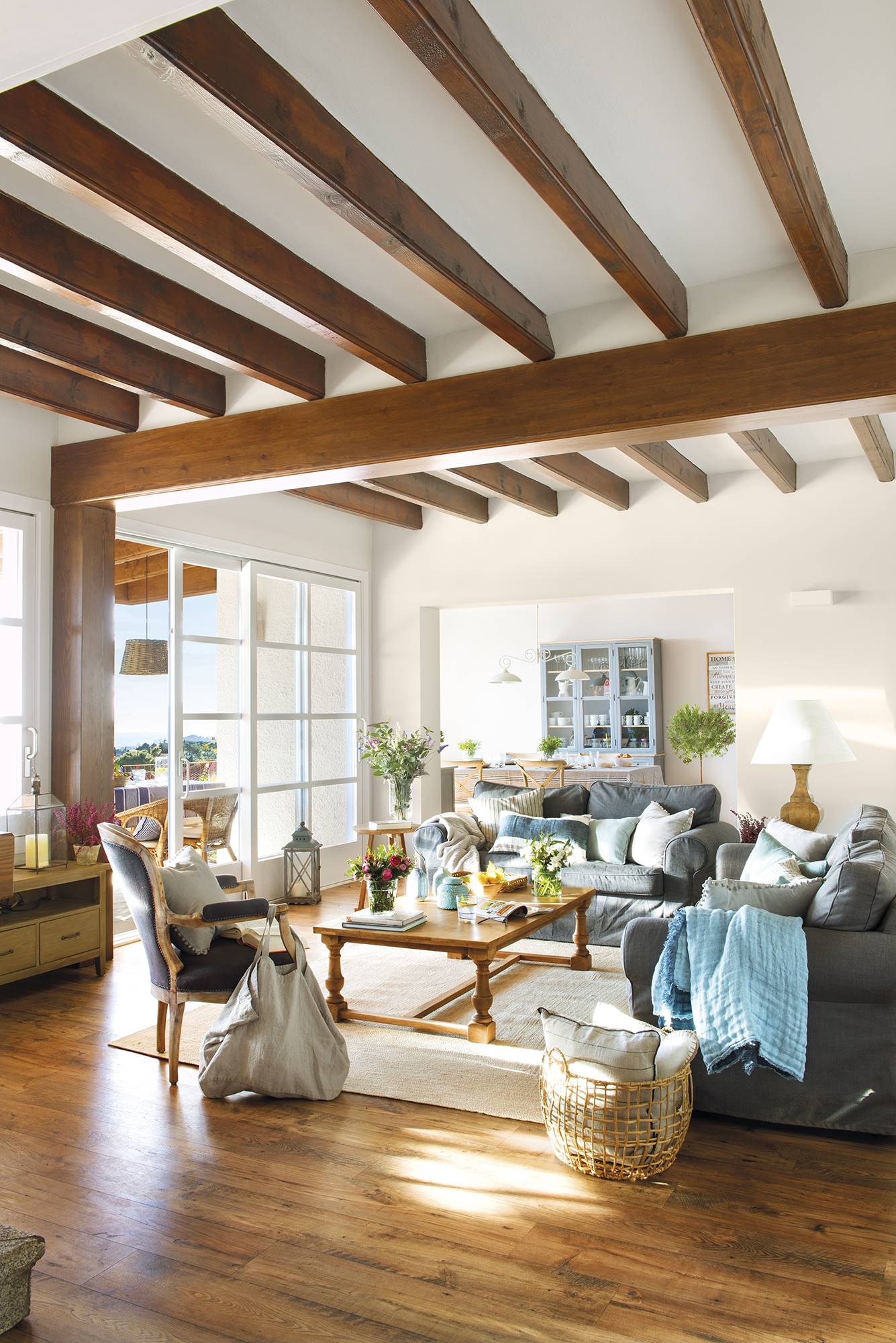 Salón con vigas de madera en el techo y tonos azules en los muebles.