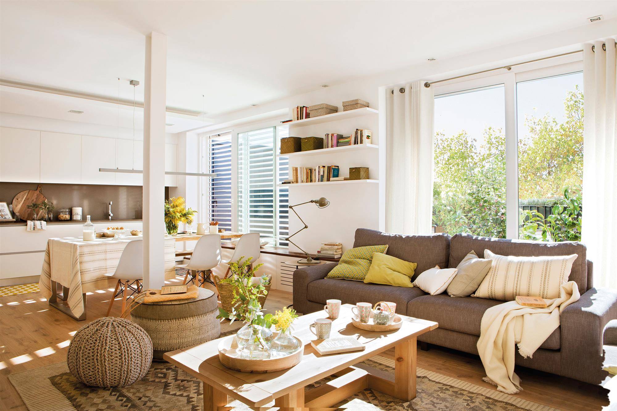 Un salón con terraza  en tonos blancos y con un gran sofá en marrón