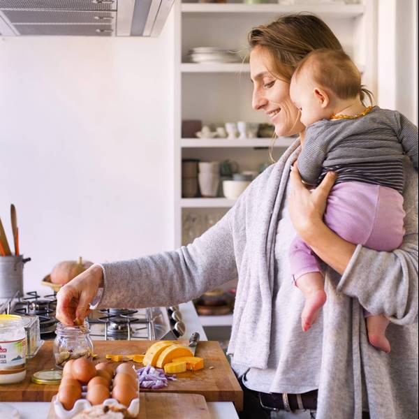 mujer cocinando con un bebe en brazos 00449778