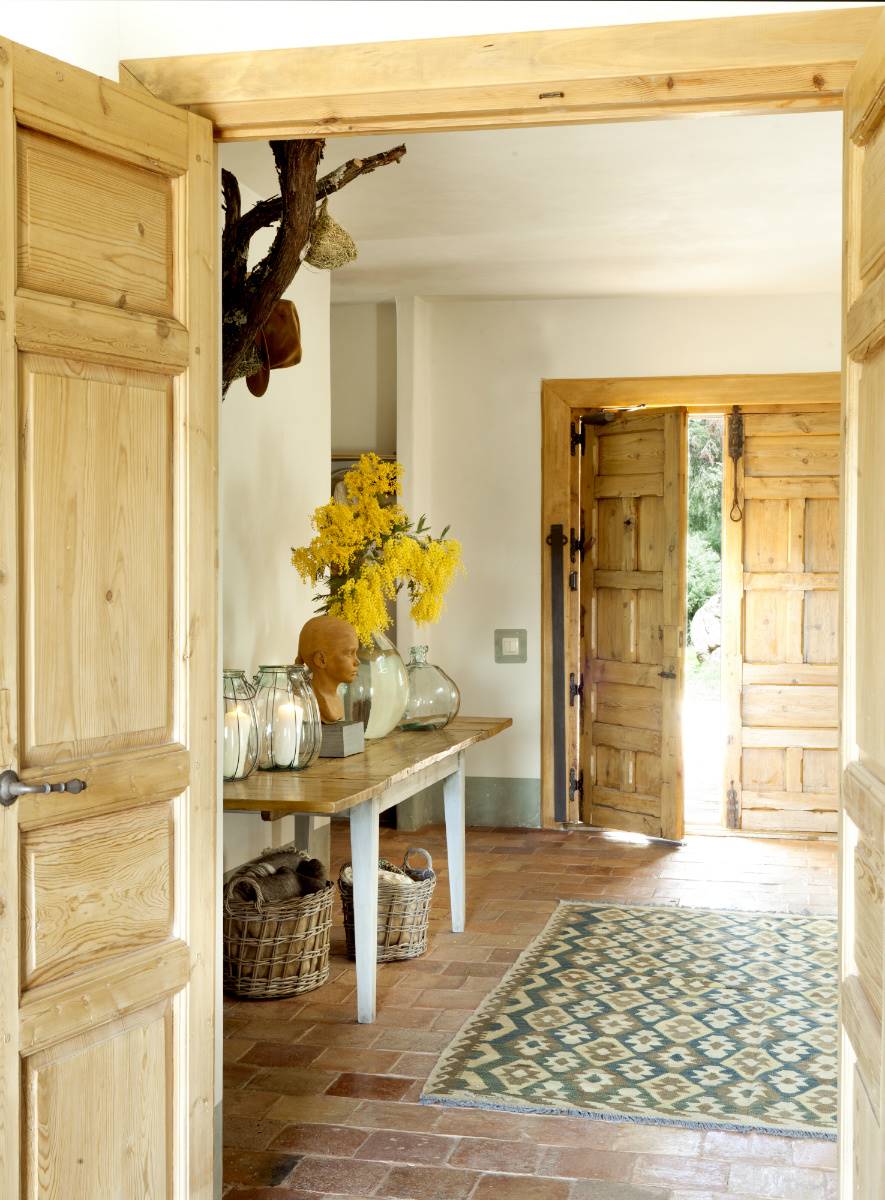 Un recibidor rústico con una mesa de madera llena de jarrones y flores.