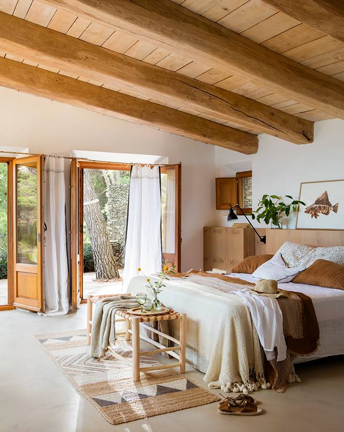 Dormitorio con techo abuhardillado y cabecero de madera.