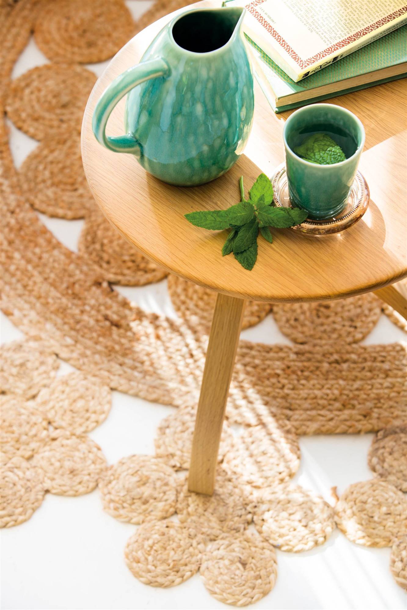 Alfombra de fibras naturales y mesa auxiliar con jarra y vaso de cerámica en color verde agua