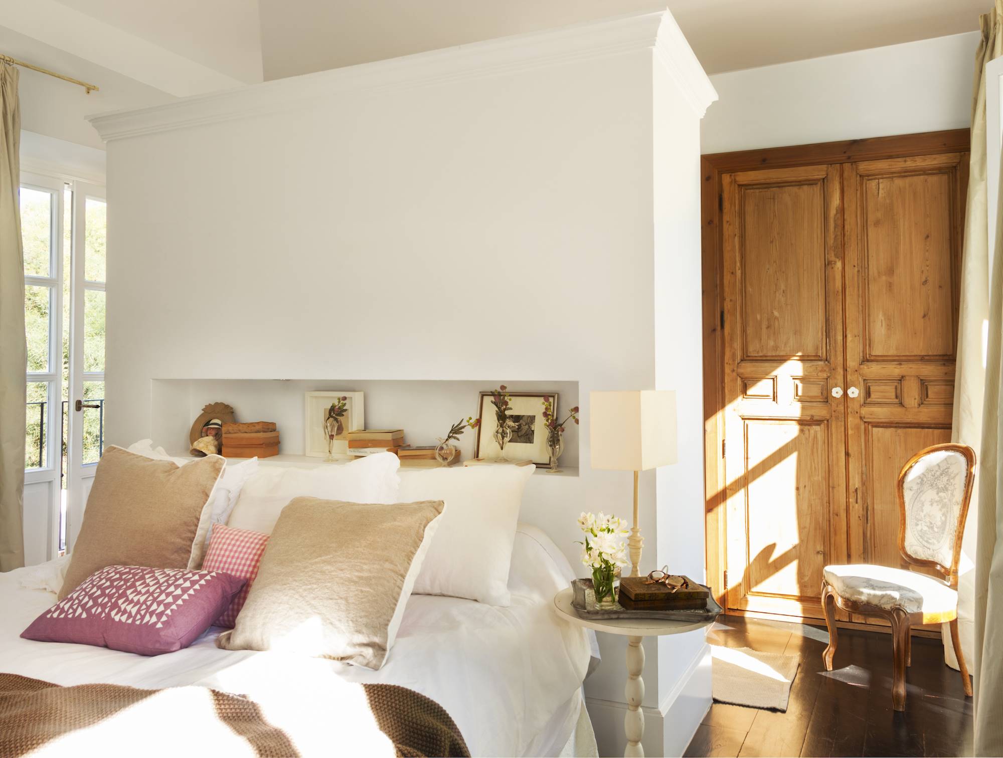 Dormitorio con gran cabecero blanco y armarios empotrados de madera