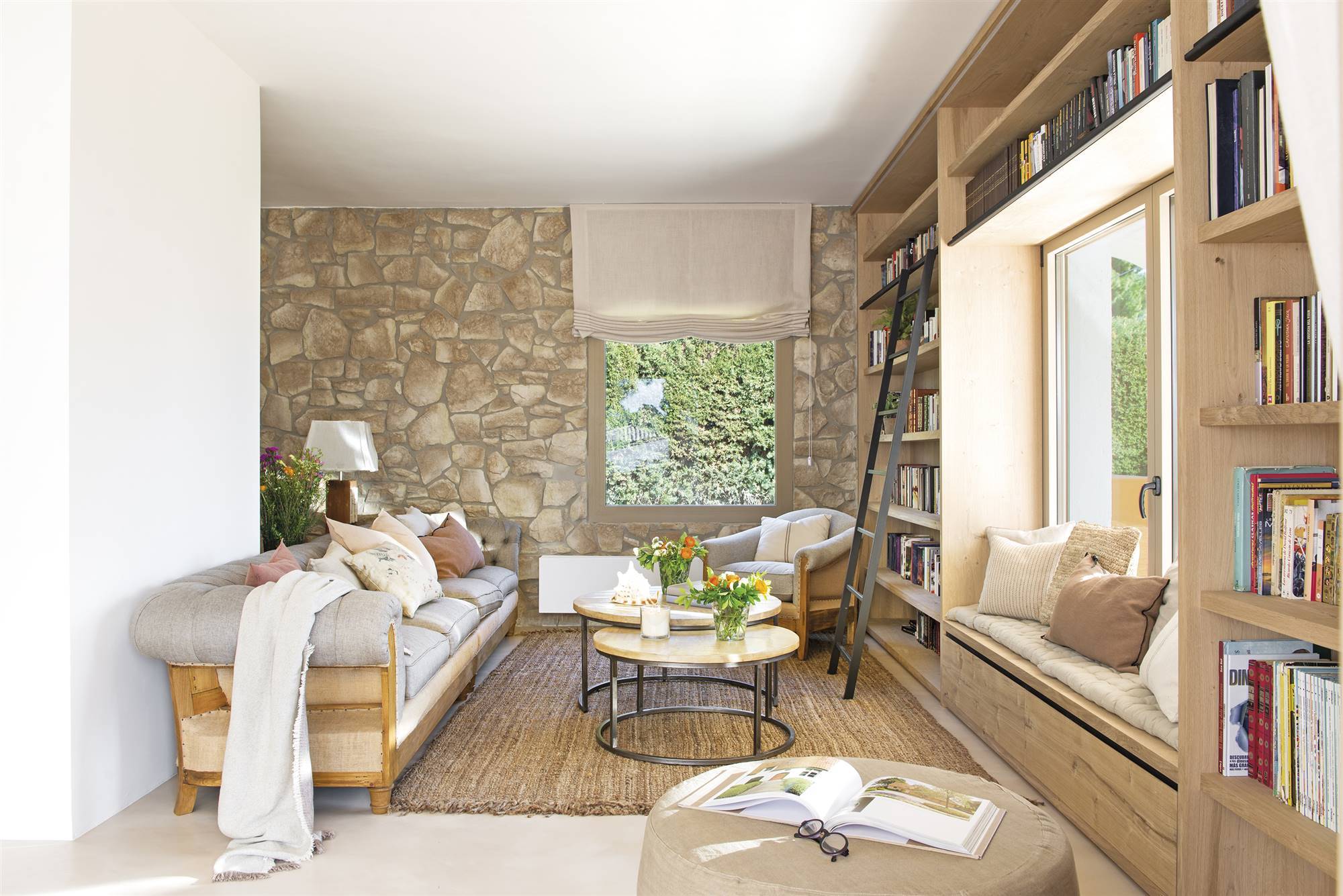 Salón con sofás blancos y revestimiento en la pared que imita la piedra. 