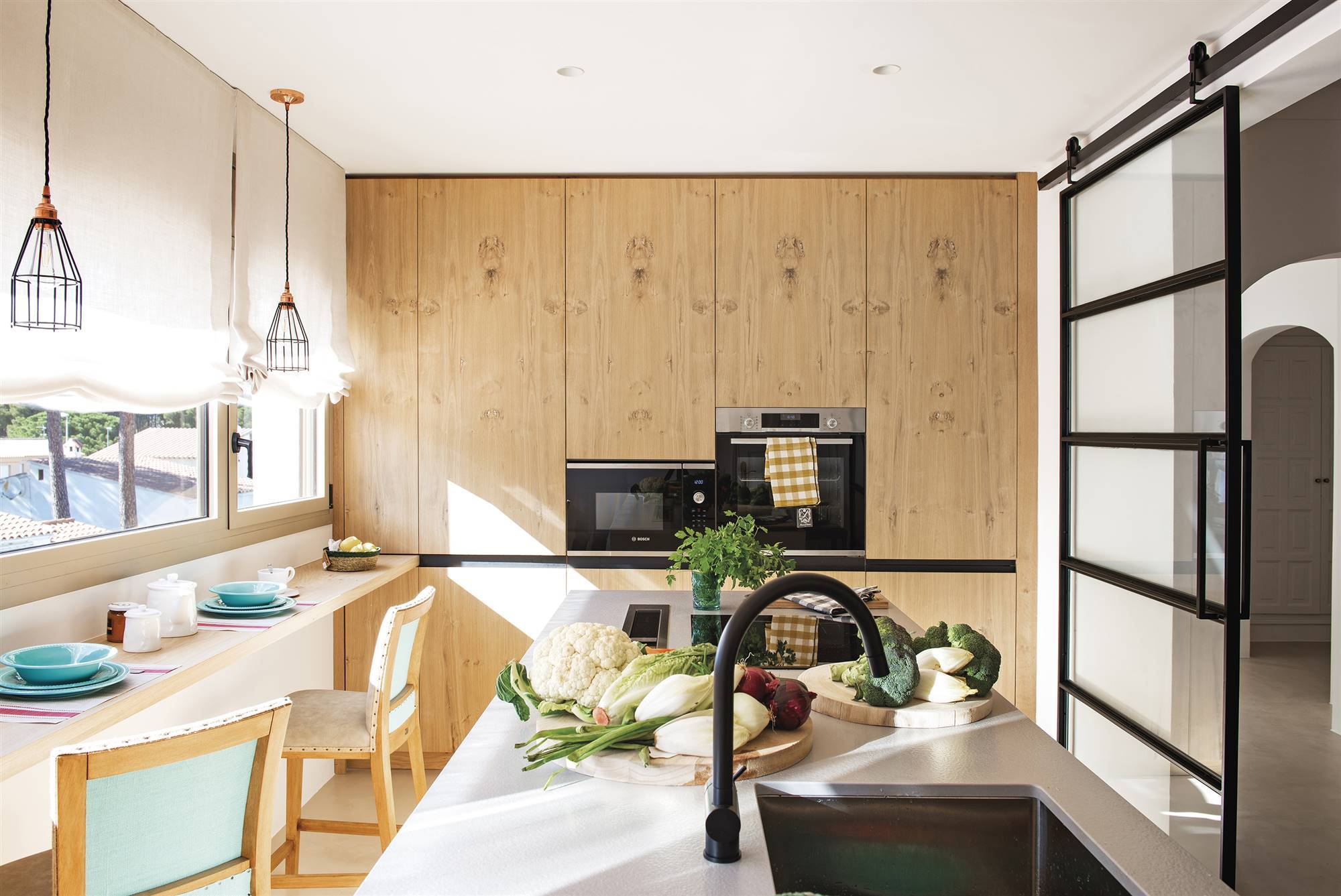 Cocina moderna con isla y muebles con frentes de madera. 