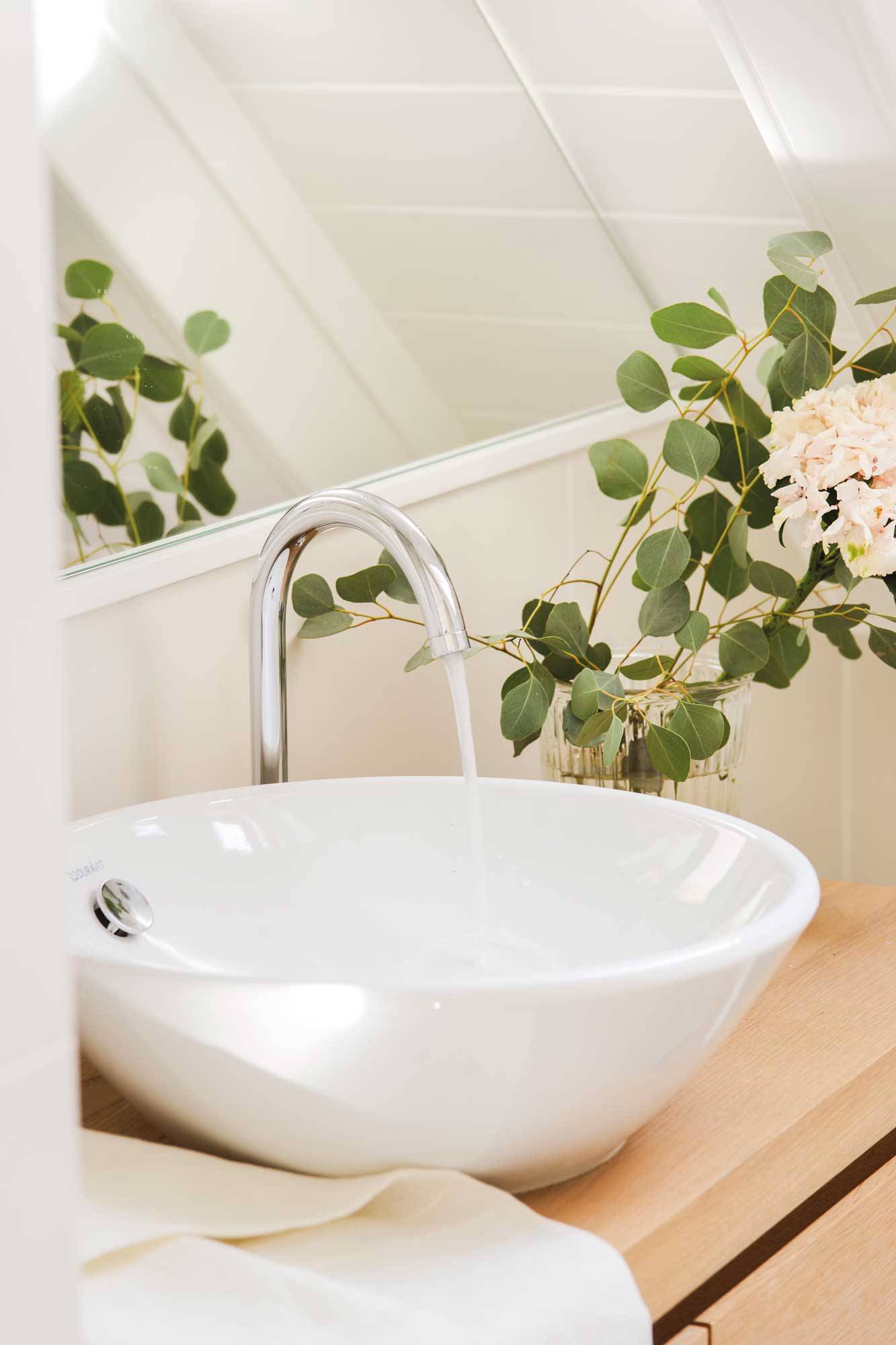 Baño con lavamanos redondo y detalle floral.