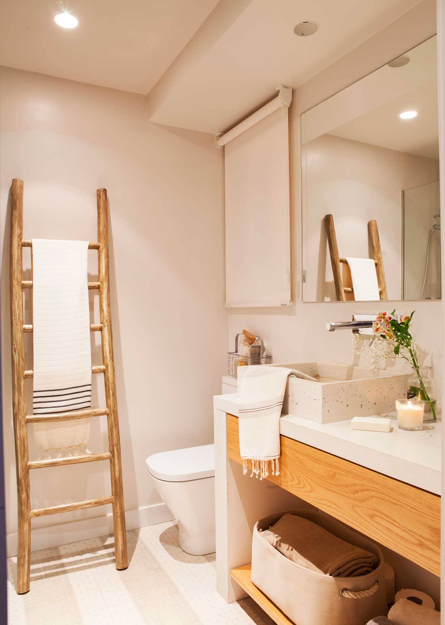 Baño pequeño con mueble bajolavabo de madera, lavamanos de gres porcelánico y escalera-toallero rústica.