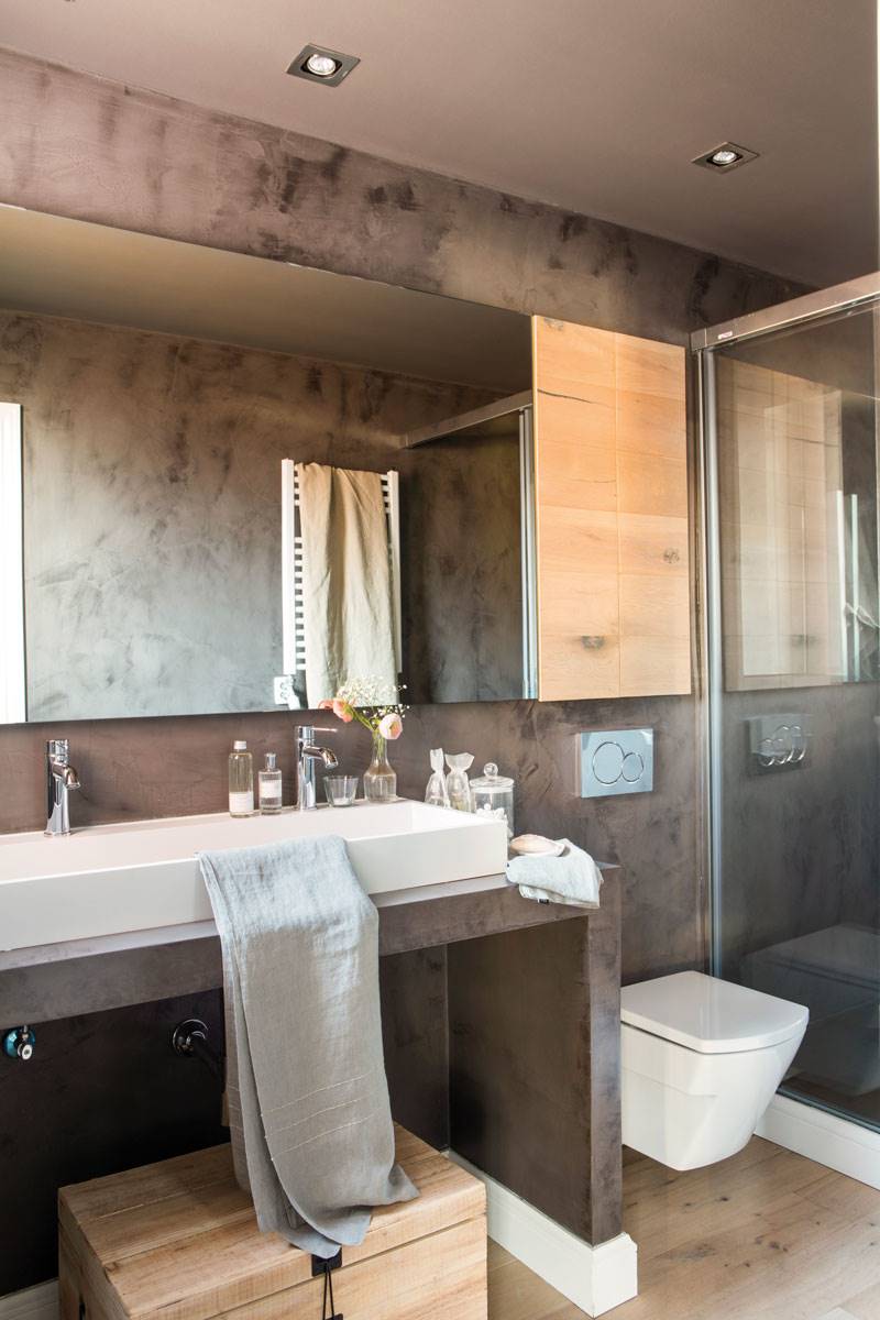 Baño gris moderno con espejo amplio y ducha con mampara. 