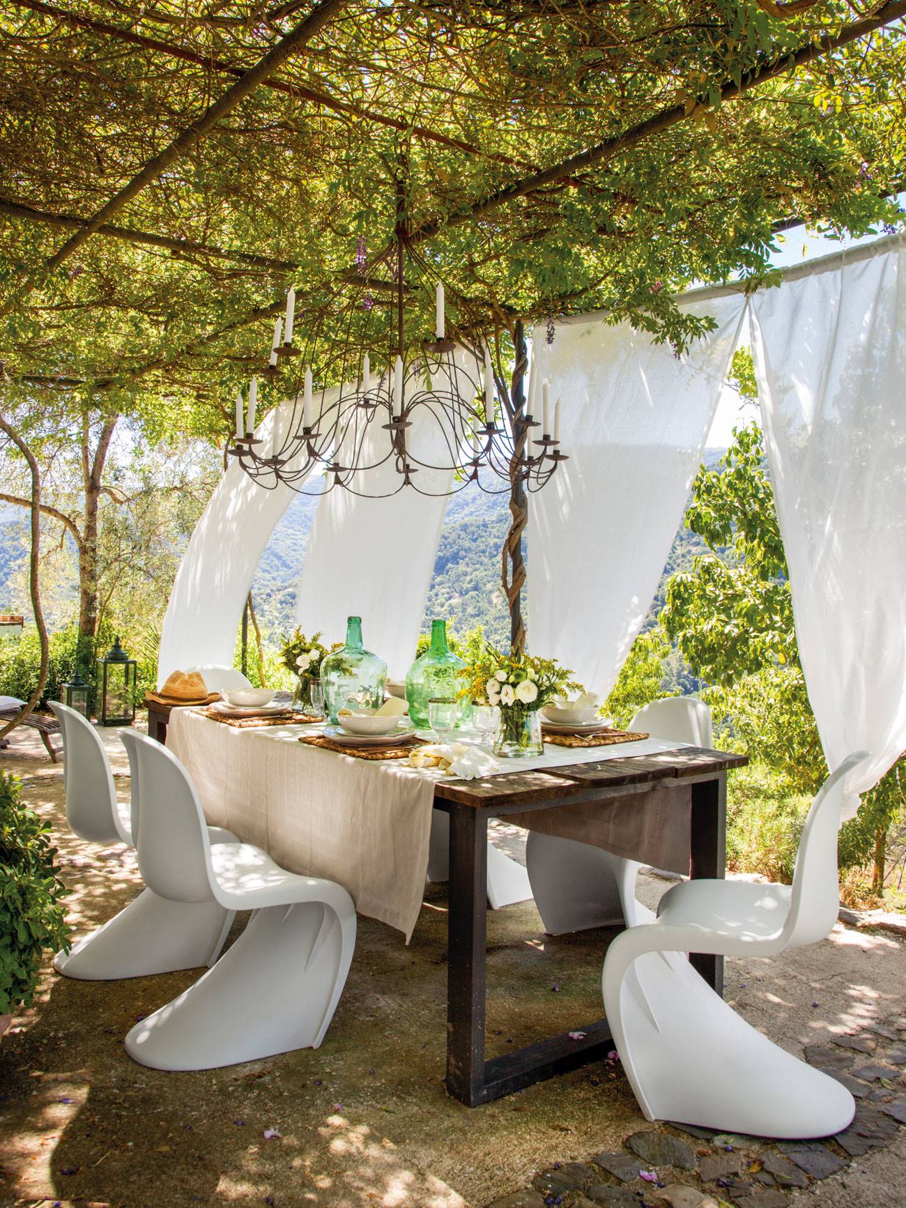 Comedor exterior con aire romántico y con sillas modelo Panton. 