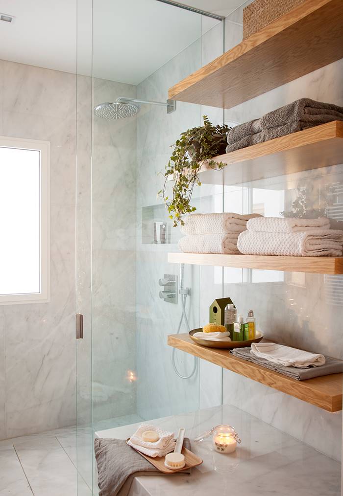 Baño con encimera, revestimiento y pavimento de mármol, ducha con mampara y ventana. 