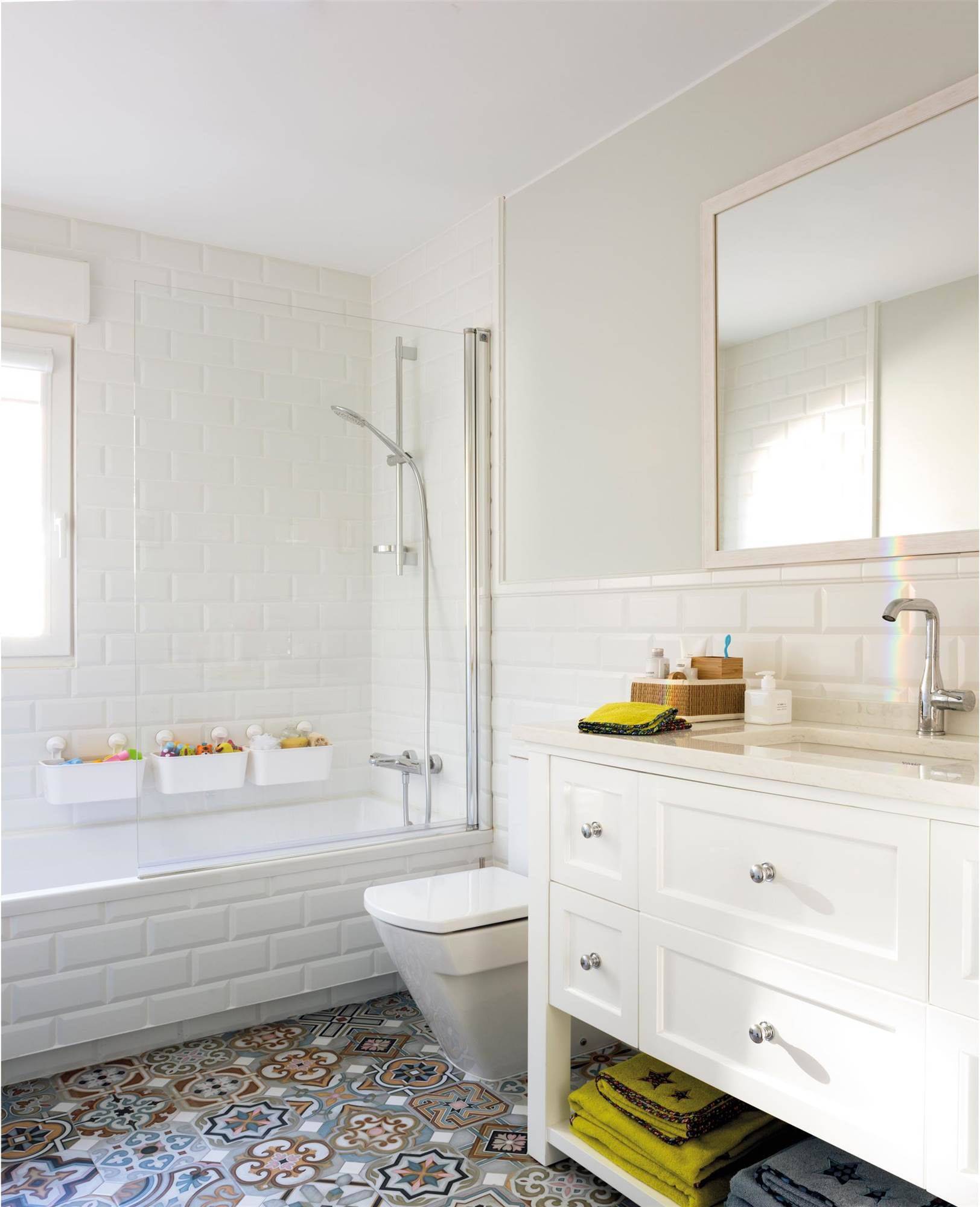Baño con azulejos tipo metro en blanco con bañera, mampara y suelo hidráulico. 