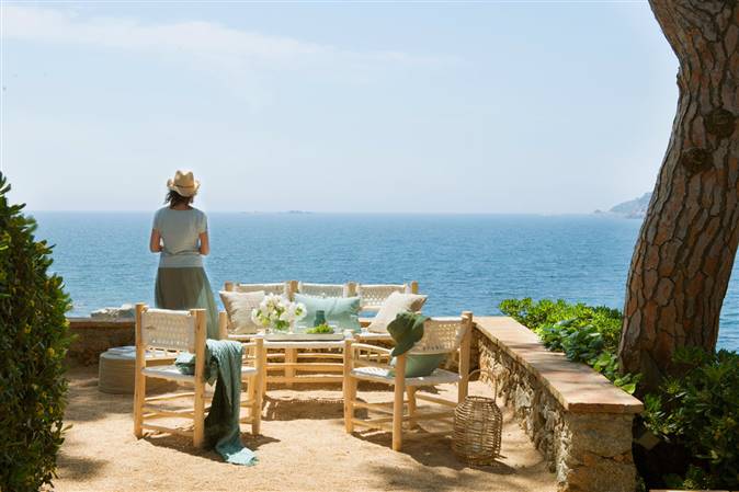 Mujer en terraza de verano con vistas al mar y conjunto de sofá de madera-485412