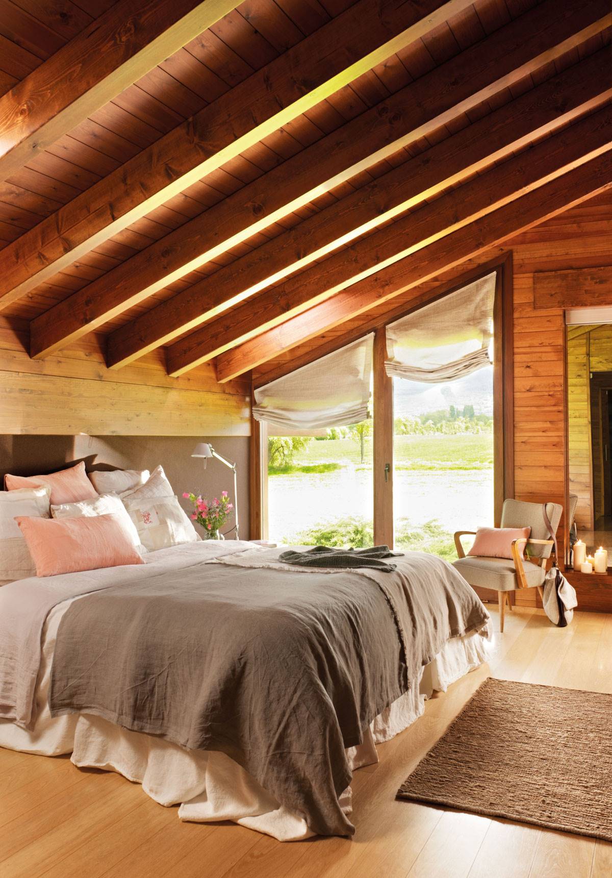 Dormitorio principal rústico con techo abuhardillado con vigas de madera, estores, butaca y velas-347186