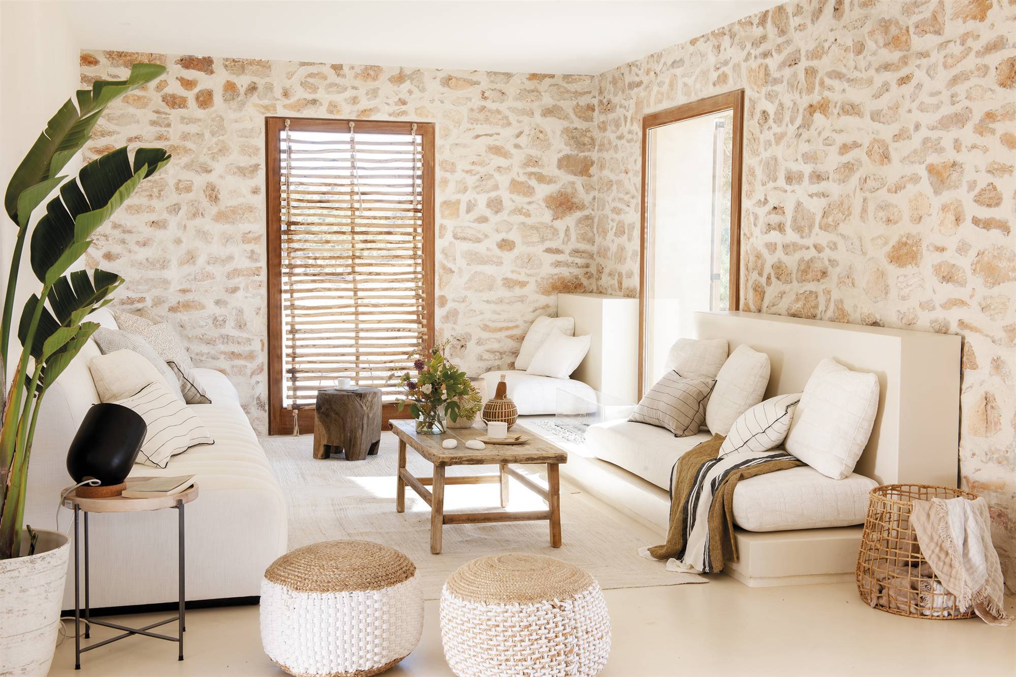 Salón blanco de casa de verano con paredes de piedra pintadas en blanco. 