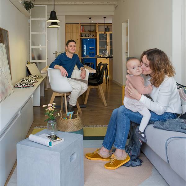 Pareja con bebé en el salón de su pequeño piso en Barcelona