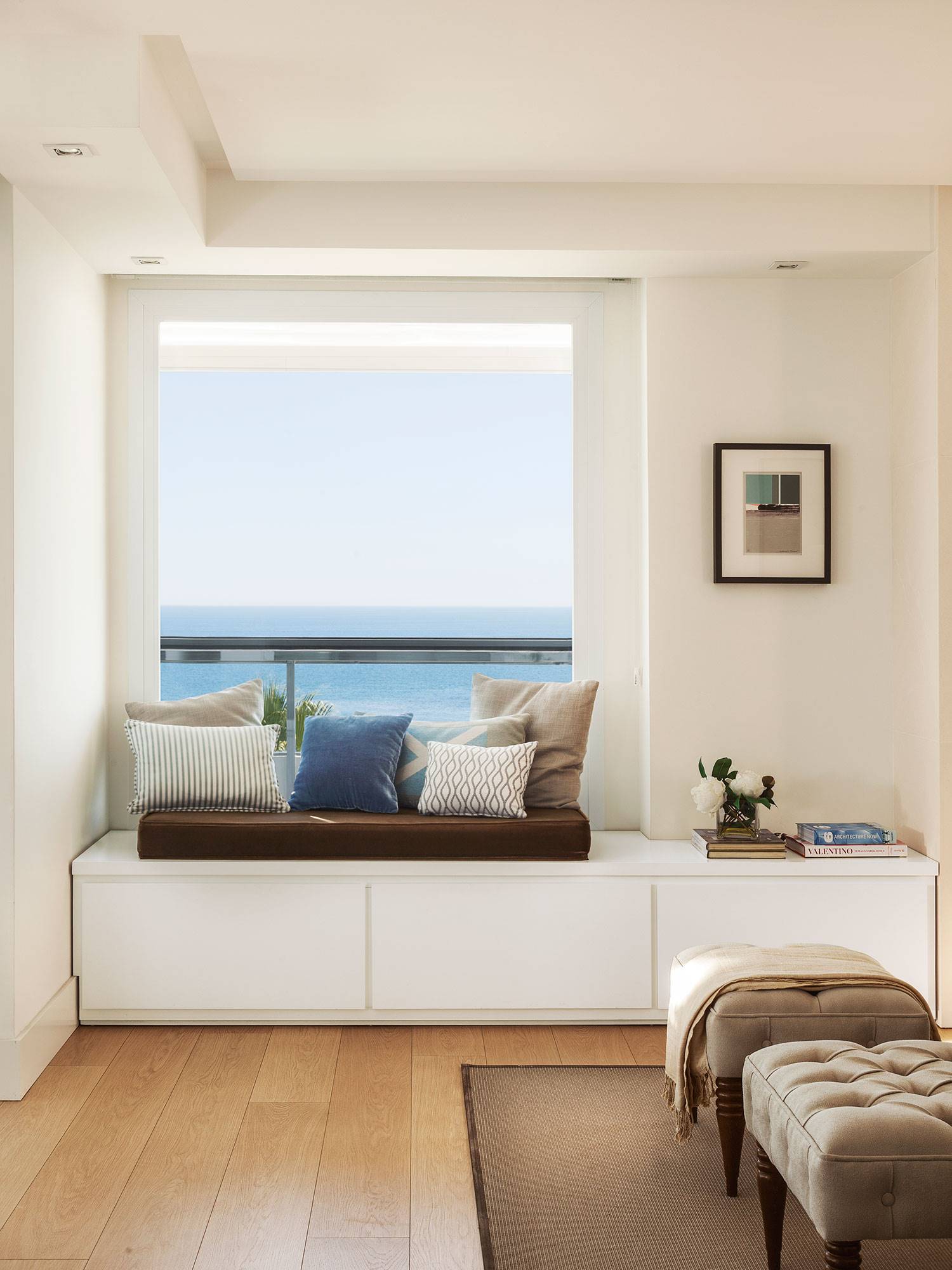 Dormitorio veraniego con banco debajo de ventana con vistas al mar