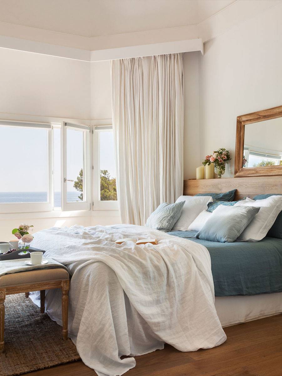 Dormitorio con vistas al mar y ropa de cama en blanco y azul