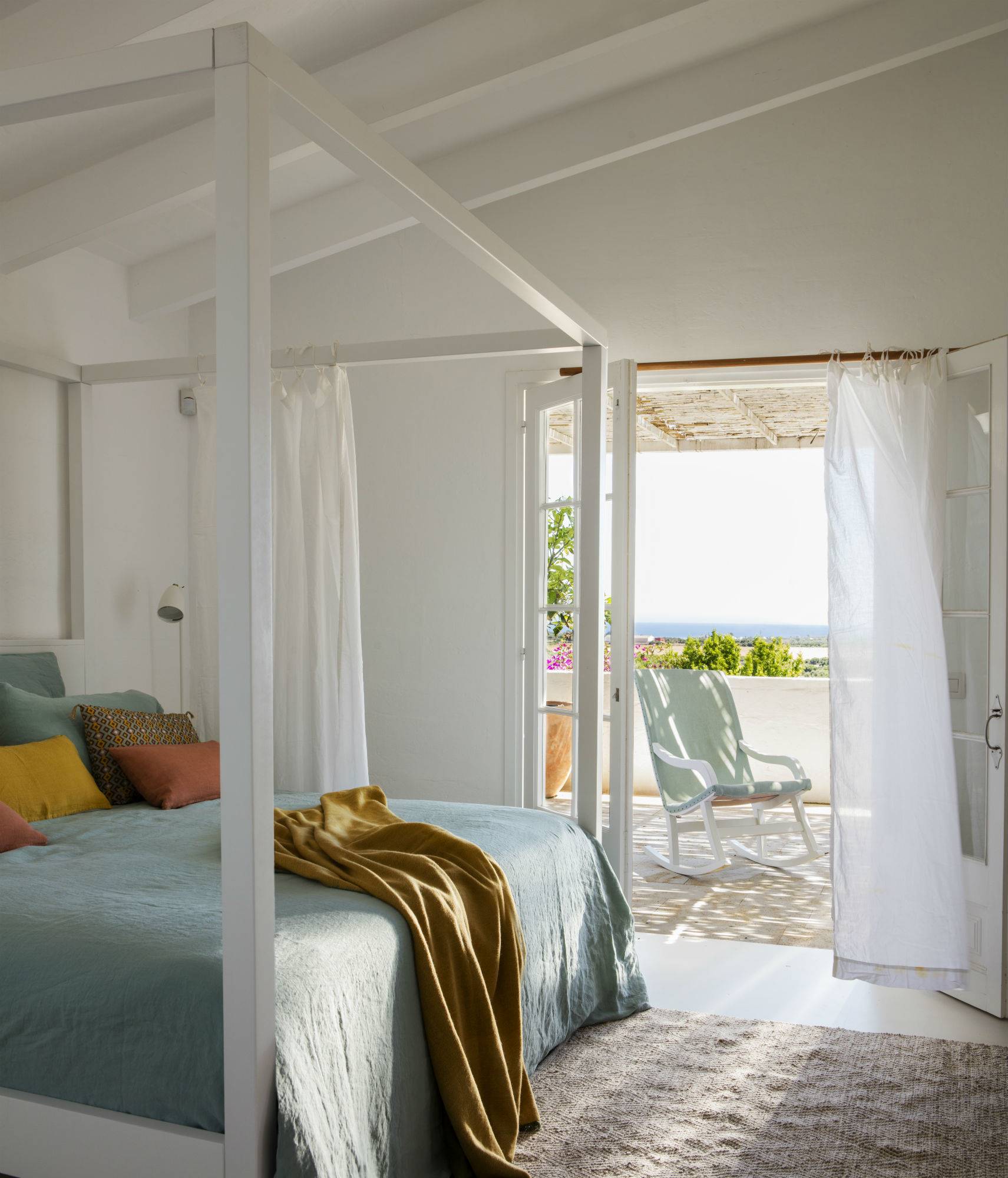 Dormitorio veraniego menorquín en tonos verdes azulados con vistas al mar