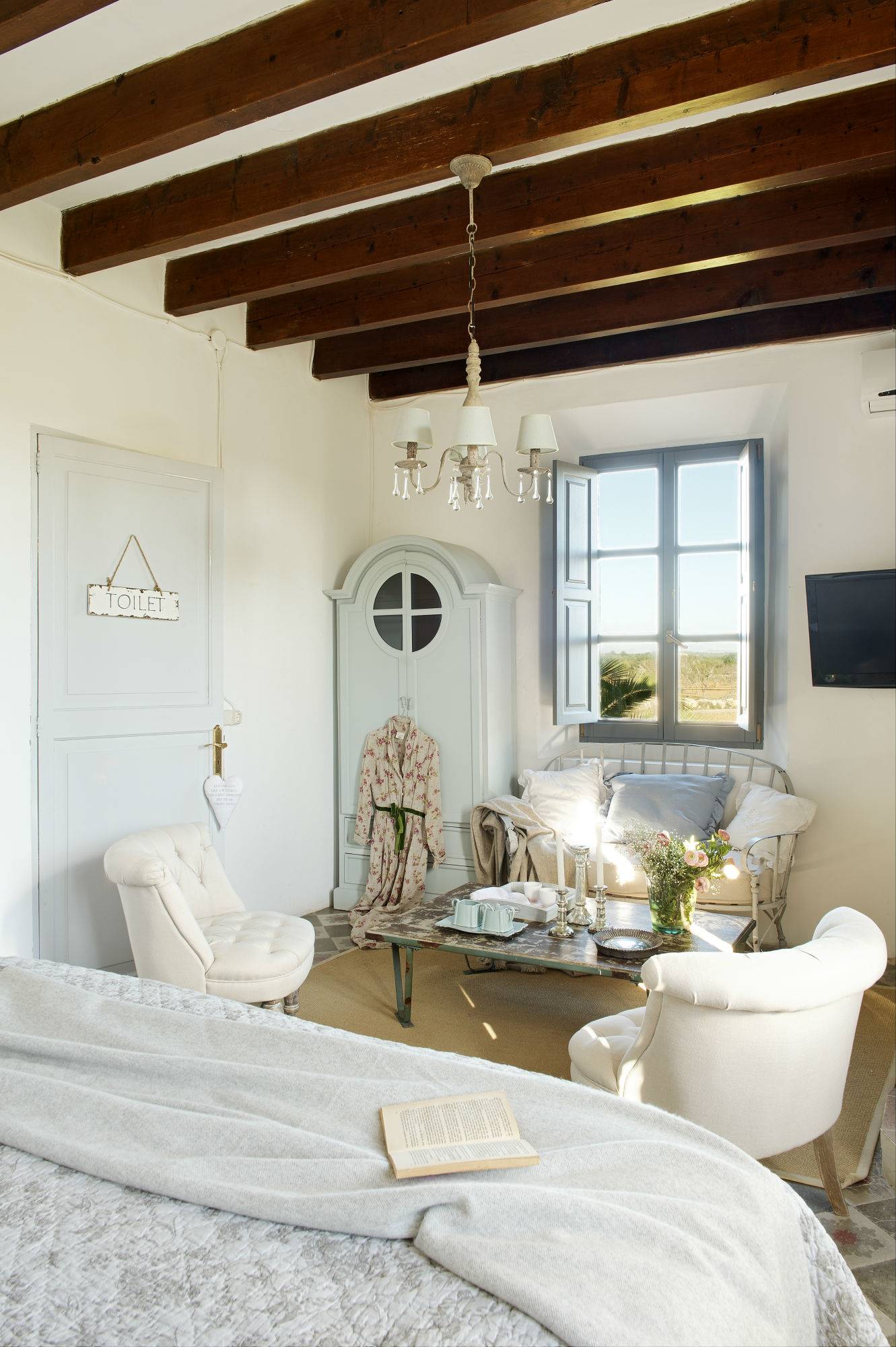 Dormitorio veraniego con butacas blancas y en tonos pastel.
