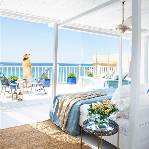 Dormitorio con paredes y techo blanco con cama de madera y gran ventanal con vistas al mar_ 00461874