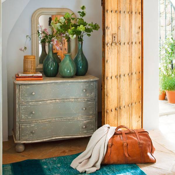 recibidor-puerta-madera-y-cómoda-restaurada-con-jarrones-verdes-y-maleta-de-piel 345177