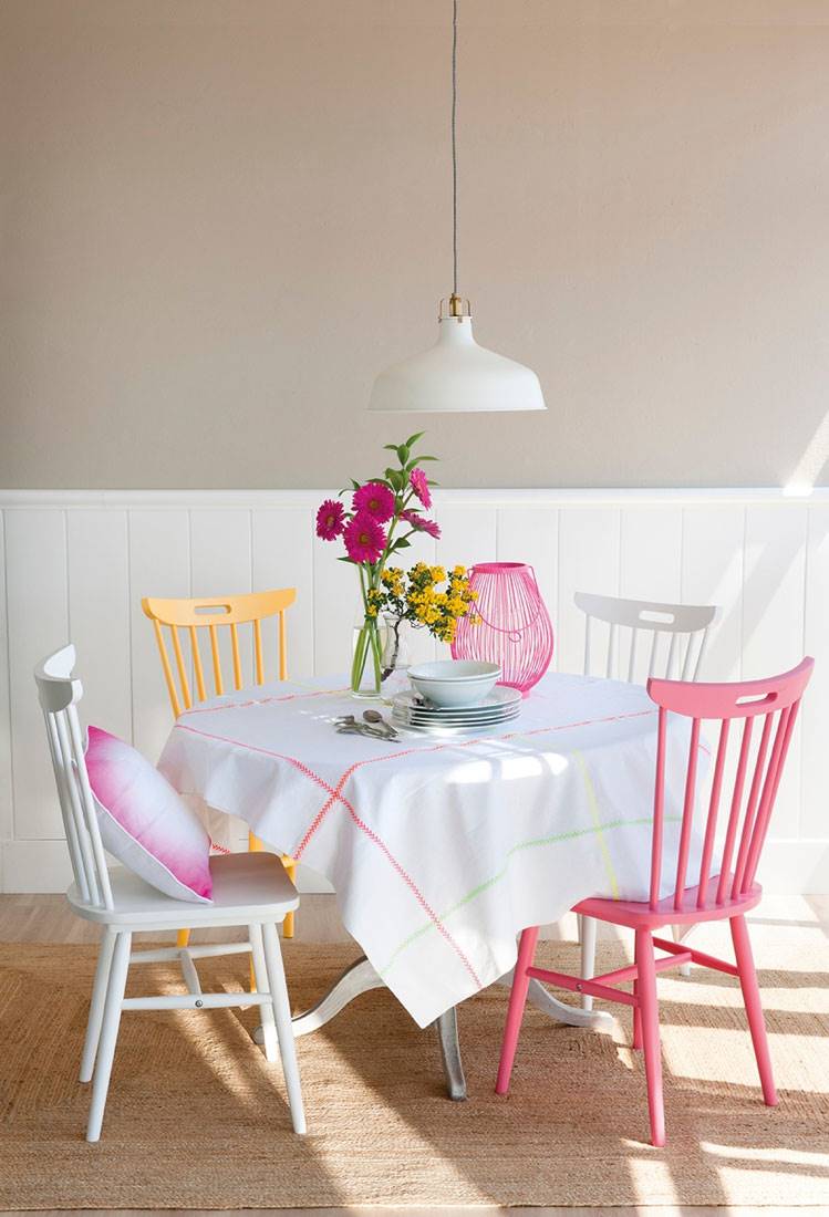 mesa-de-comedor-con-mantel-blanco-y-jarron-flores-y-sillas-de-colores